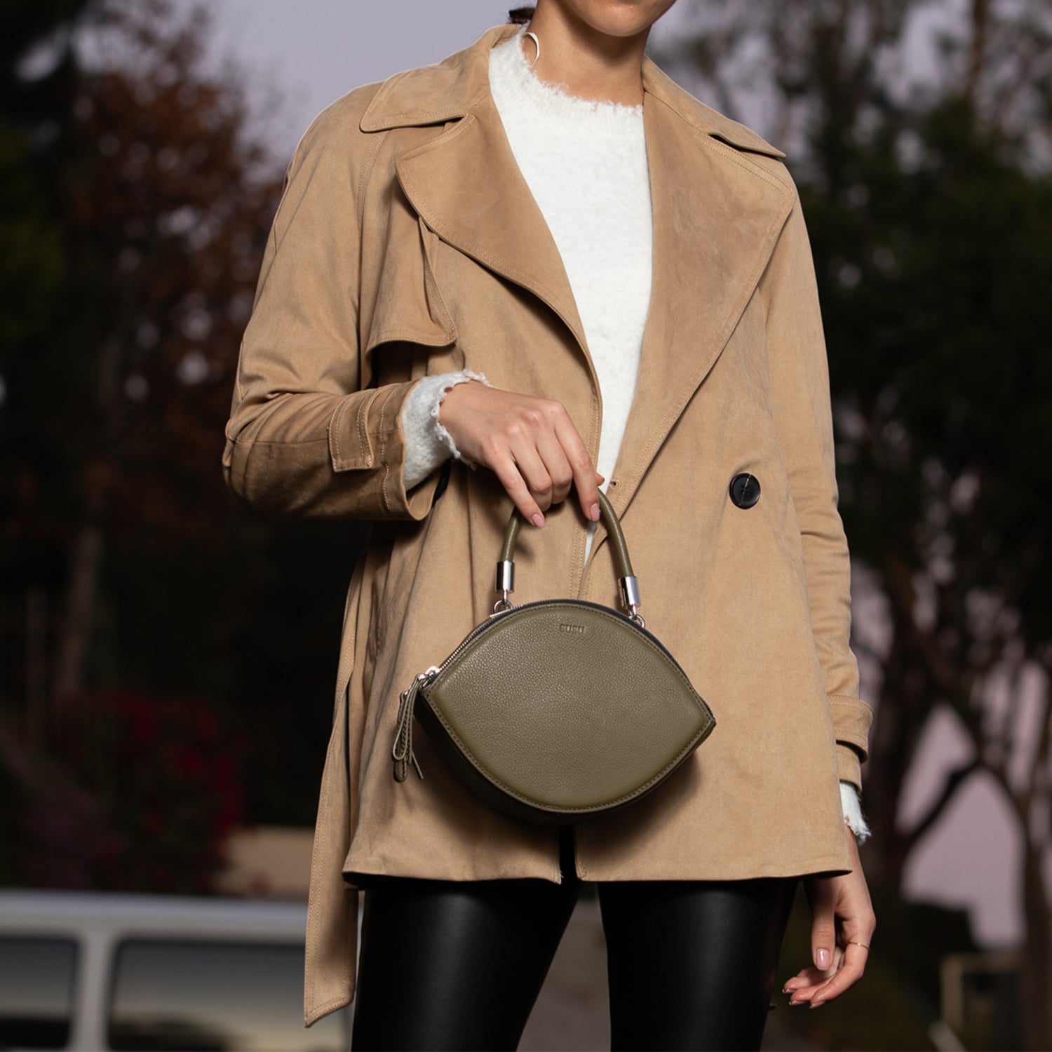 Olive green leather circle crossbody bag with silver hardware and teal lining, featuring adjustable strap and double zipper compartments.