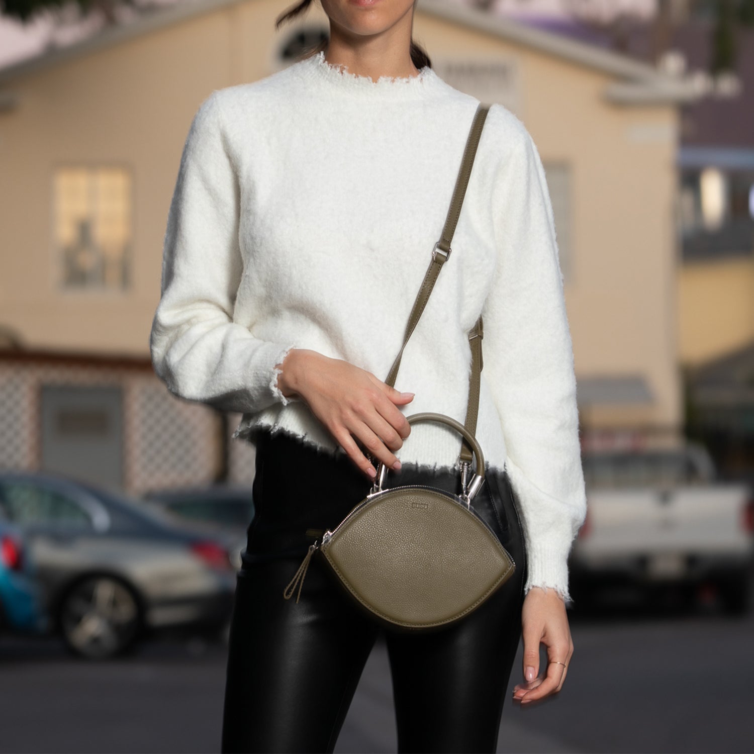 Olive green leather circle crossbody bag with silver hardware and teal lining, featuring adjustable strap and double zipper compartments.