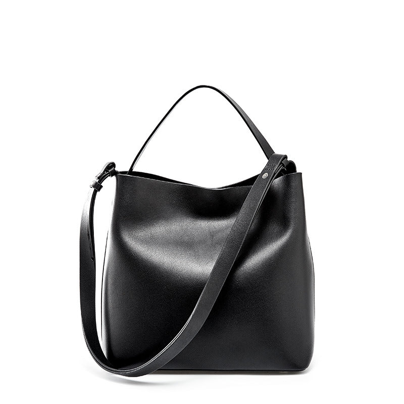 Lady's Simple Solid Color Portable Messenger Bag made of cowhide, featuring a soft handle and magnetic buckle closure, in a stylish bucket bag design.