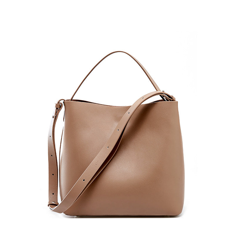 Lady's Simple Solid Color Portable Messenger Bag made of cowhide, featuring a soft handle and magnetic buckle closure, in a stylish bucket bag design.