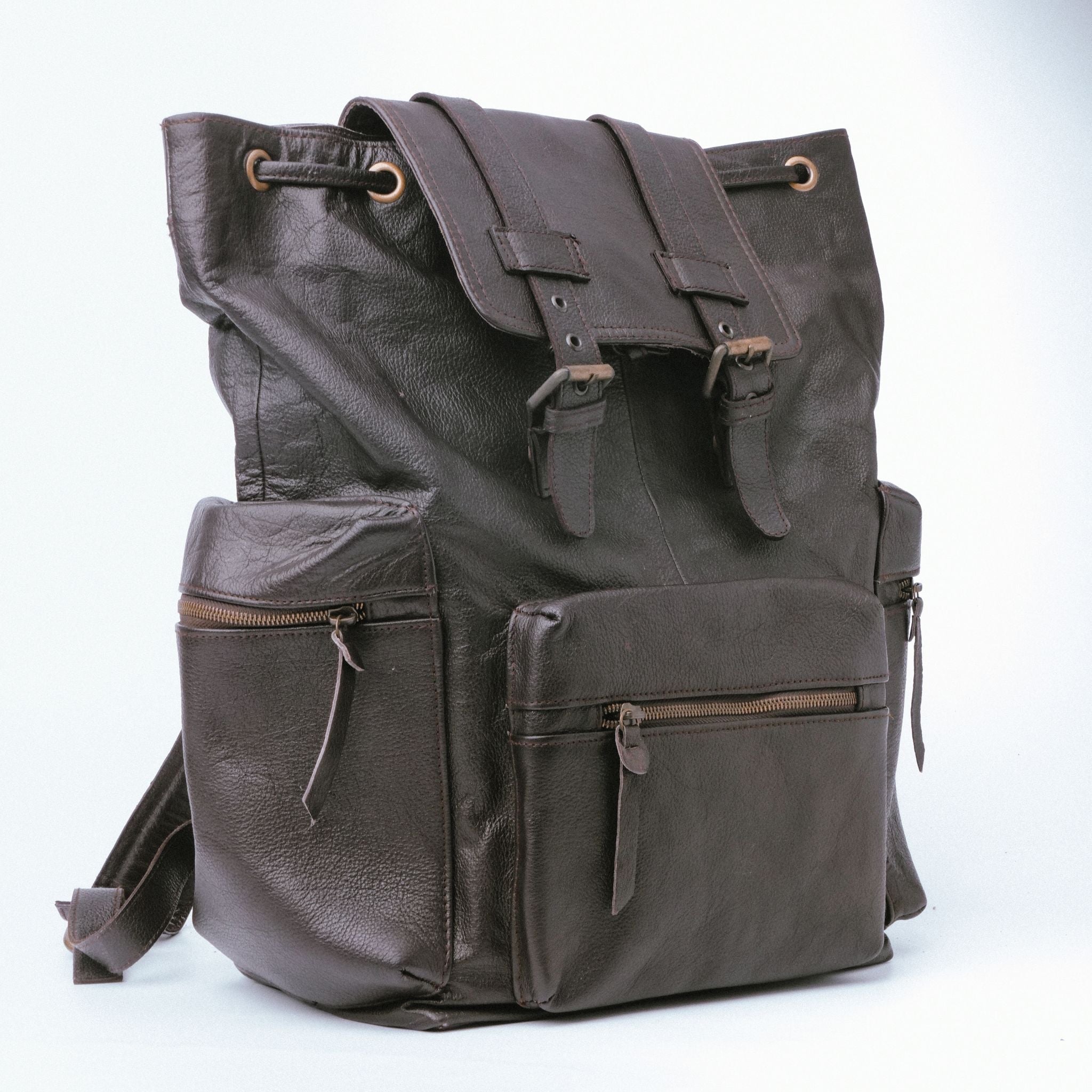 Brown leather backpack with double adjustable straps and golden hardware, featuring side zipper pockets and a top handle.