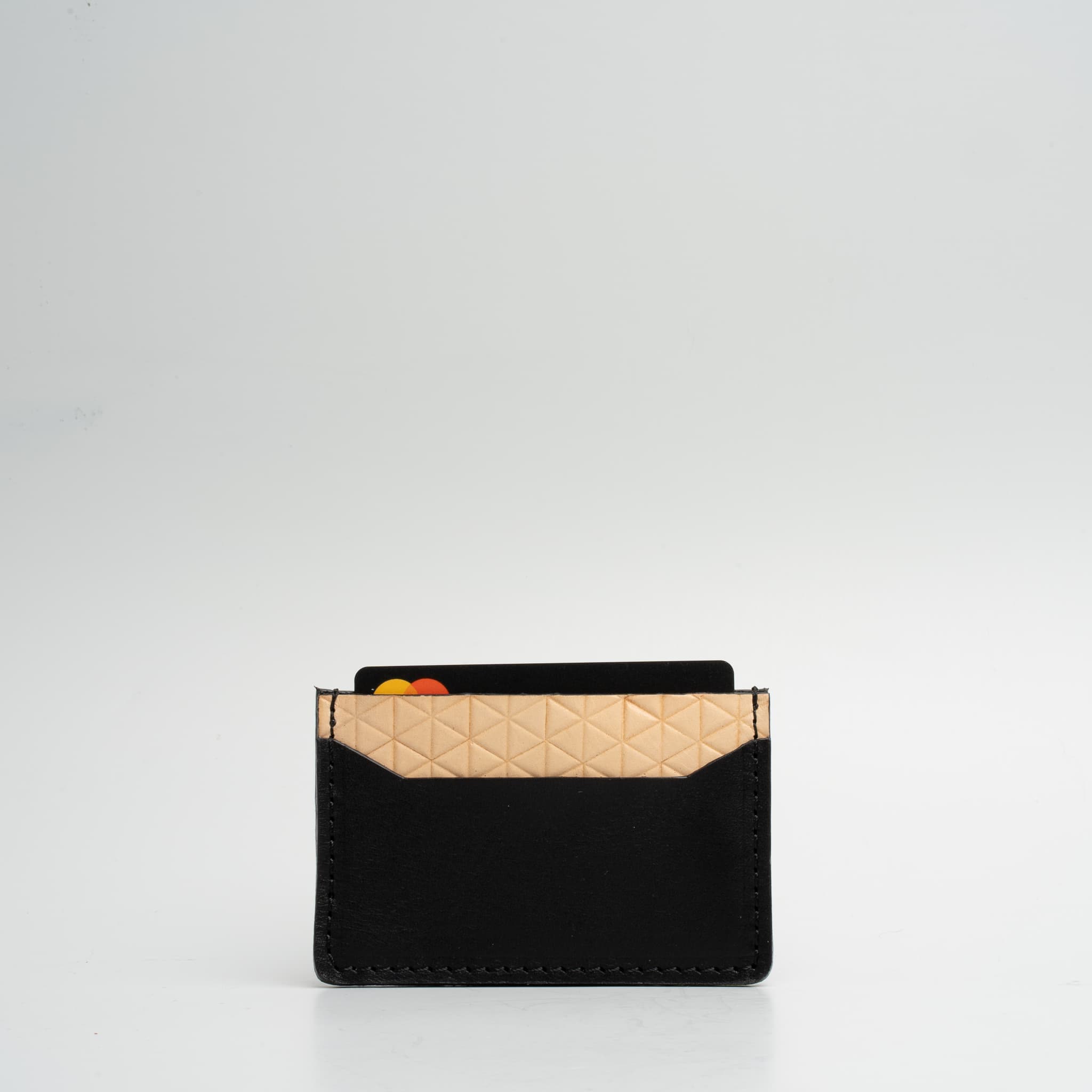 Leather card holder featuring a geometric net design, handcrafted from Italian vegetable tanned leather, holding two cards.