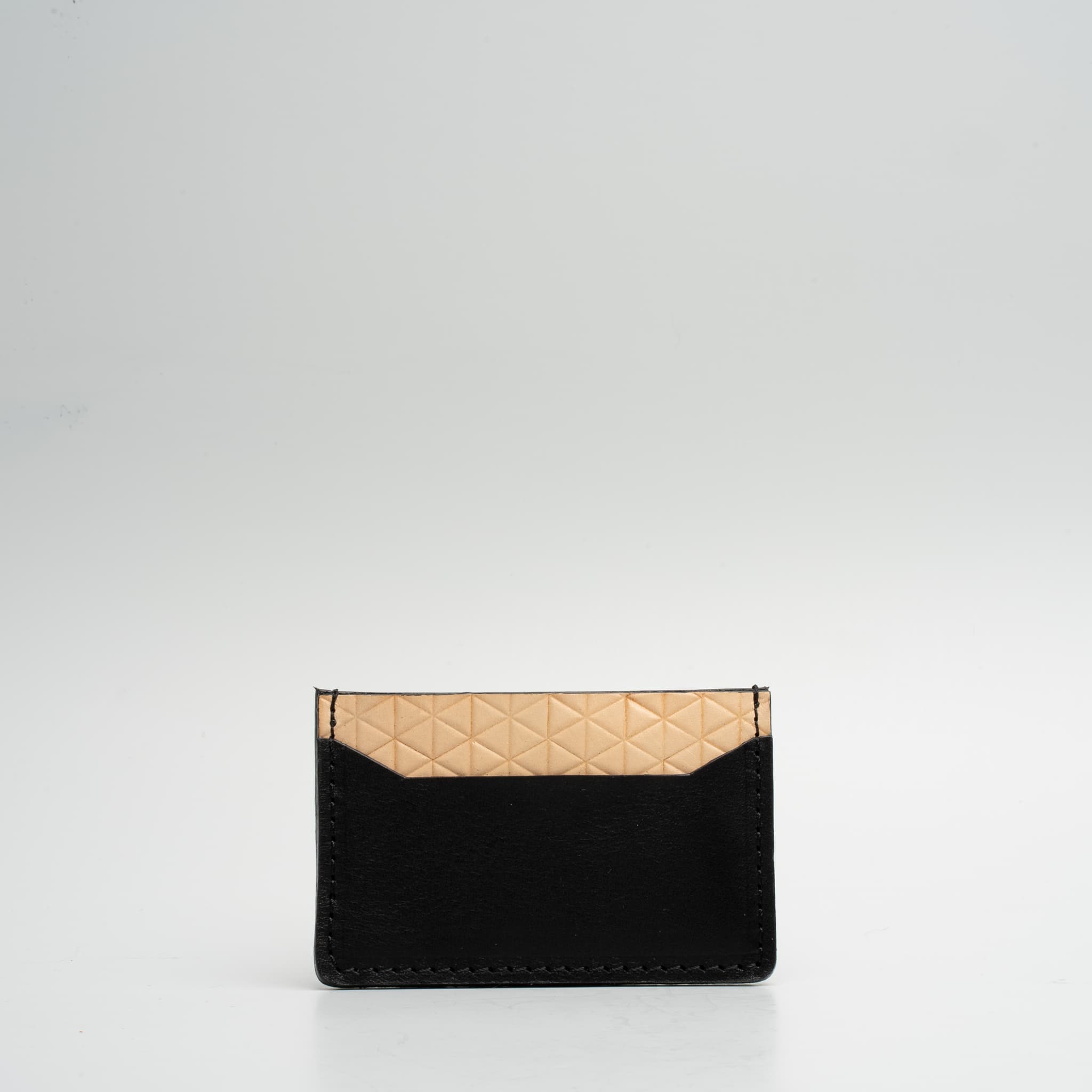 Leather card holder featuring a geometric net design, handcrafted from Italian vegetable tanned leather, holding two cards.