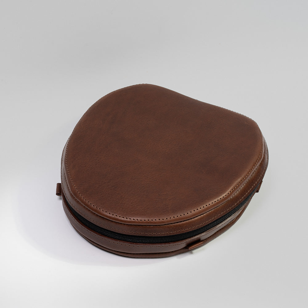 Brown leather case for AirPods Max, crafted from full-grain Italian leather with a soft lining and adjustable strap loops.