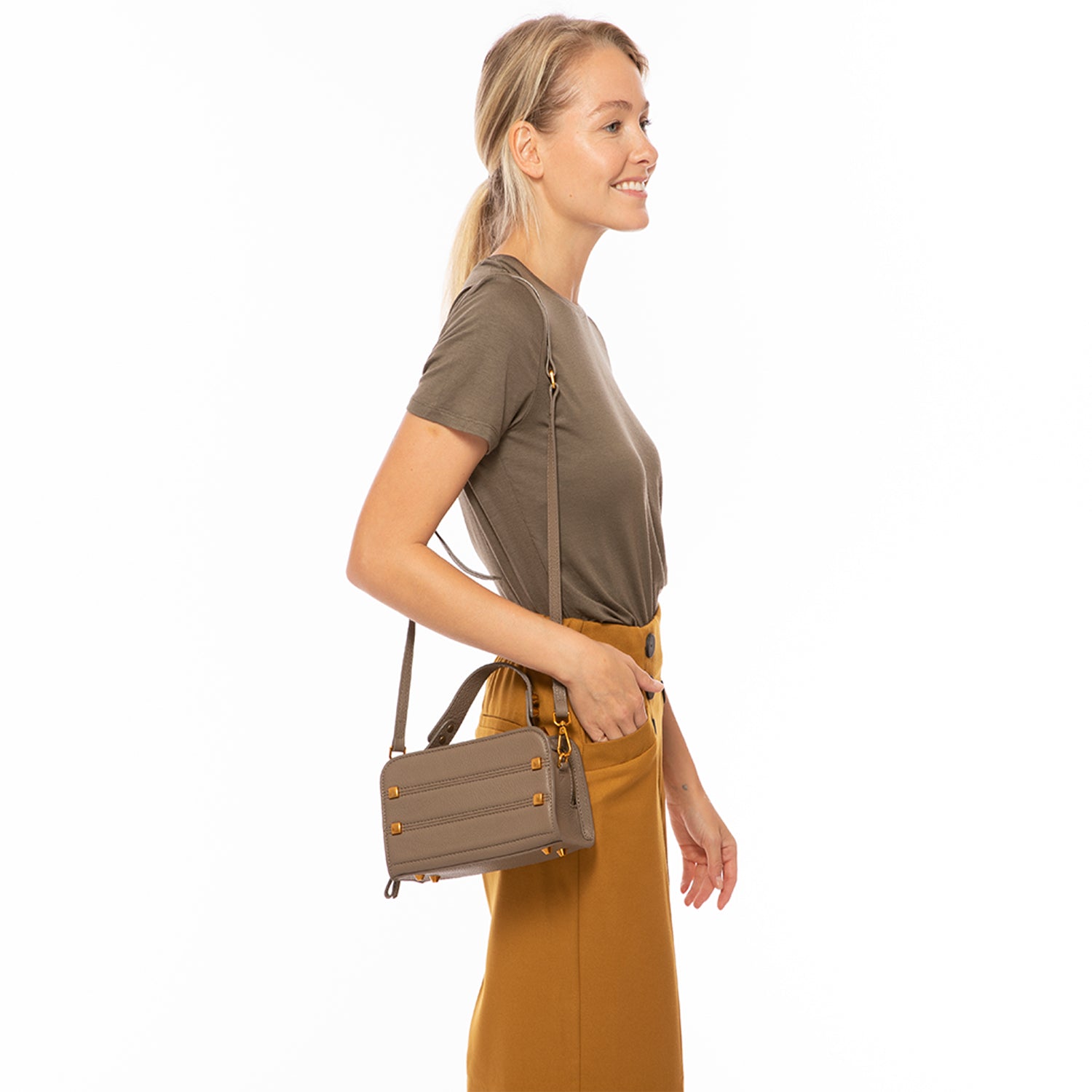 Mocha brown leather crossbody bag with rose gold studs and hardware, featuring a boxy silhouette and adjustable strap.