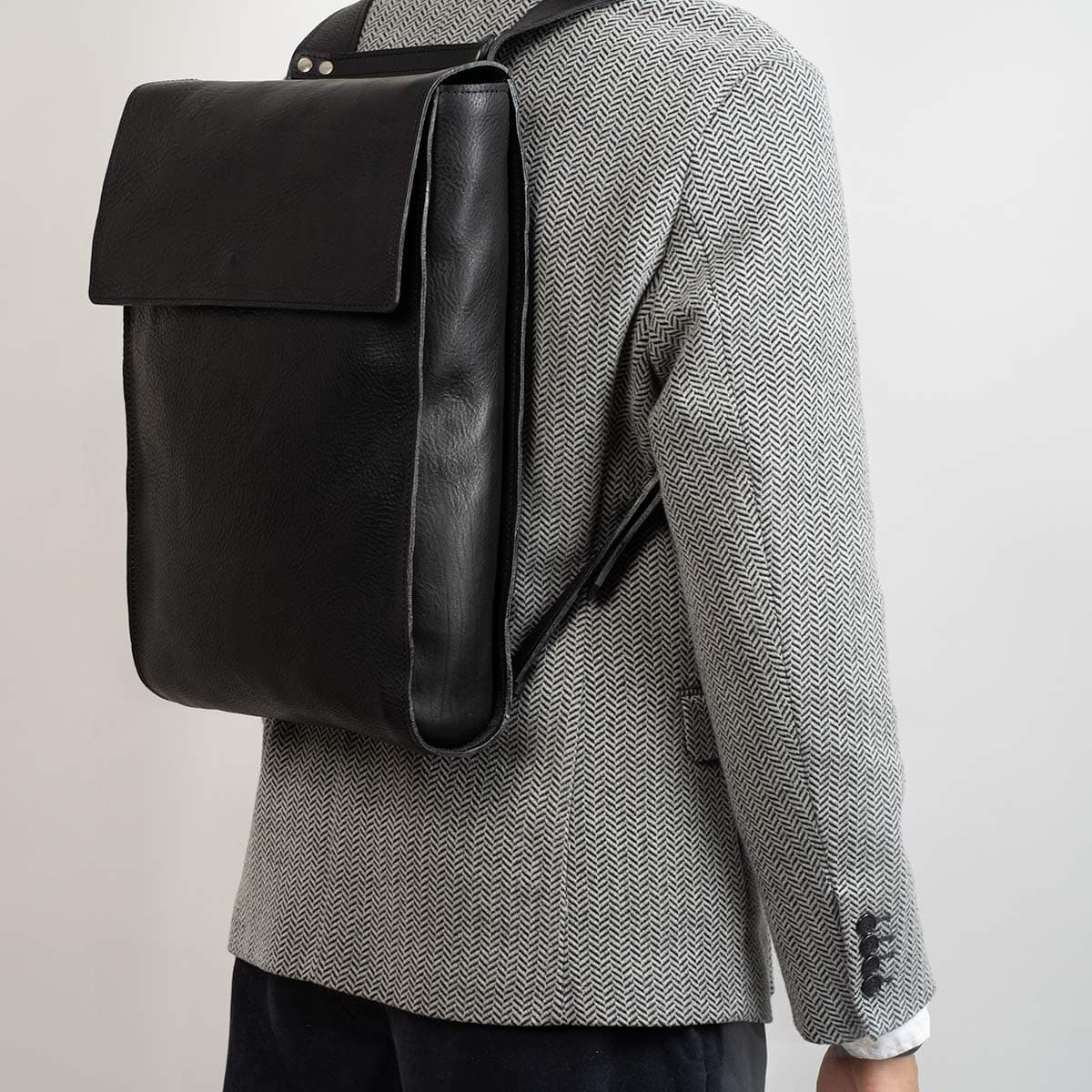 Tan leather laptop backpack with adjustable straps and multiple pockets, showcasing its minimalist design and eco-friendly materials.