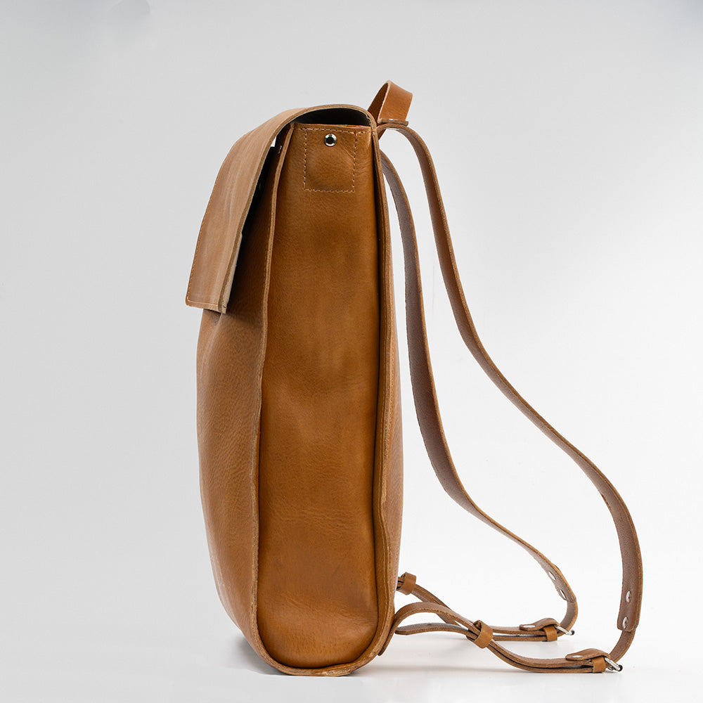 Tan leather laptop backpack with adjustable straps and multiple pockets, showcasing its minimalist design and eco-friendly materials.