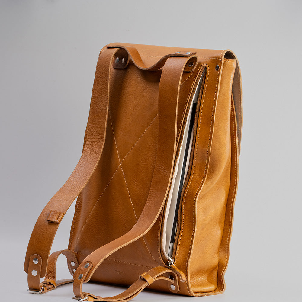 Tan leather laptop backpack with adjustable straps and multiple pockets, showcasing its minimalist design and eco-friendly materials.