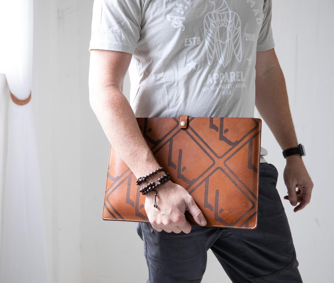 Personalized leather laptop sleeve made from genuine full grain leather, featuring a secure strap and brass snap, ideal for 13"-15" laptops.