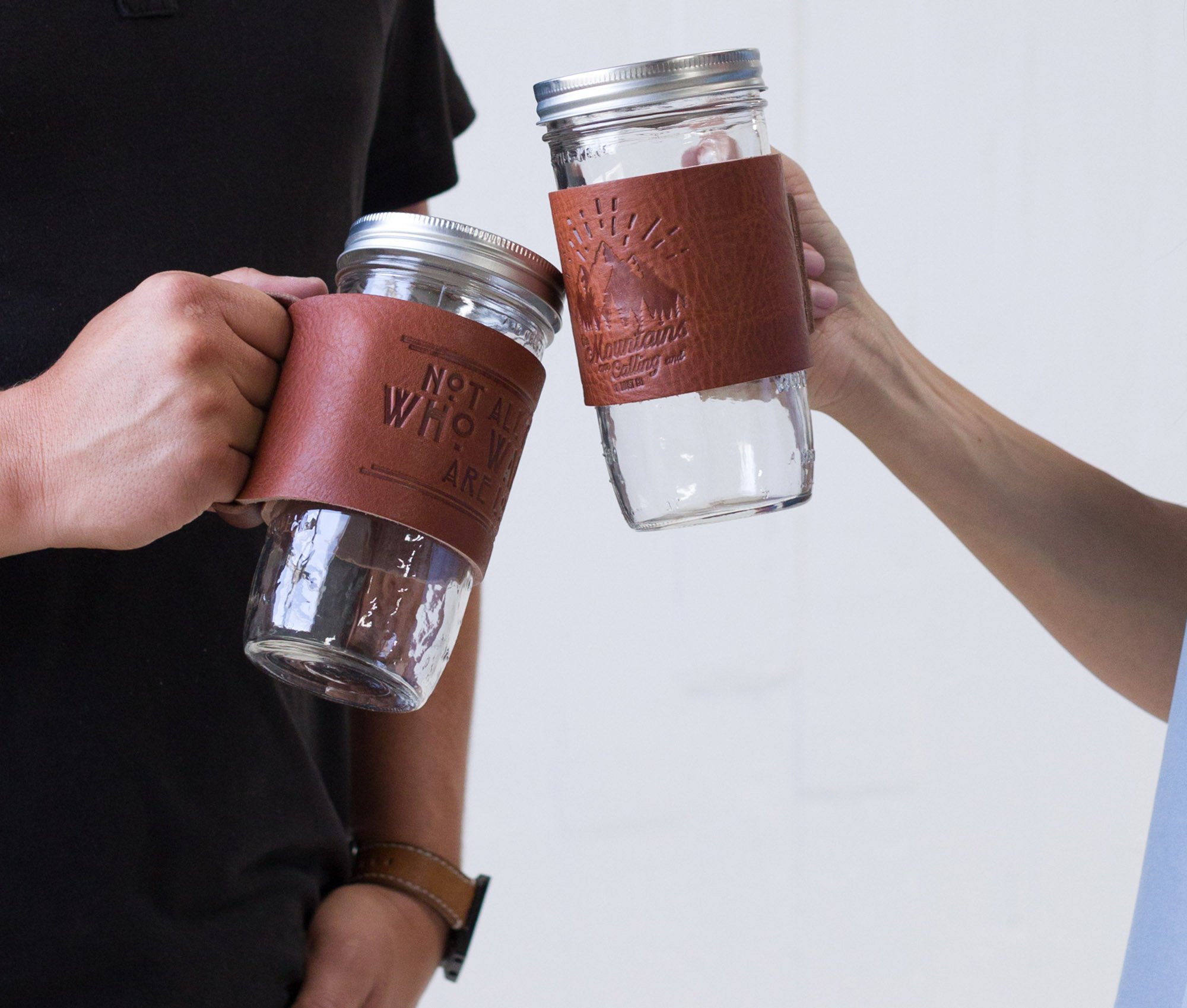 Leather Mason Jar Coozie hugging a Mason jar, showcasing its hand-stitched design and riveted handle.