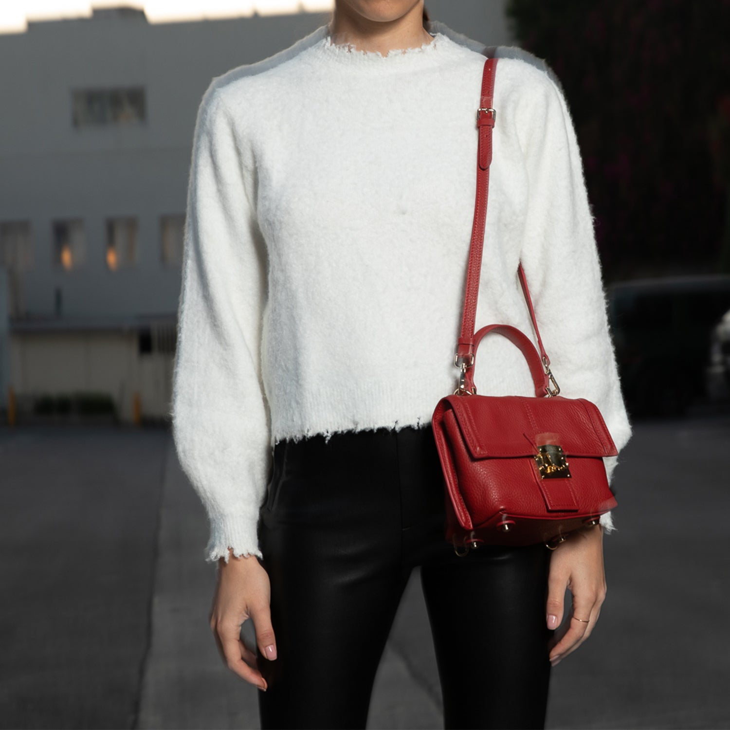 Person with red handbag outdoors.