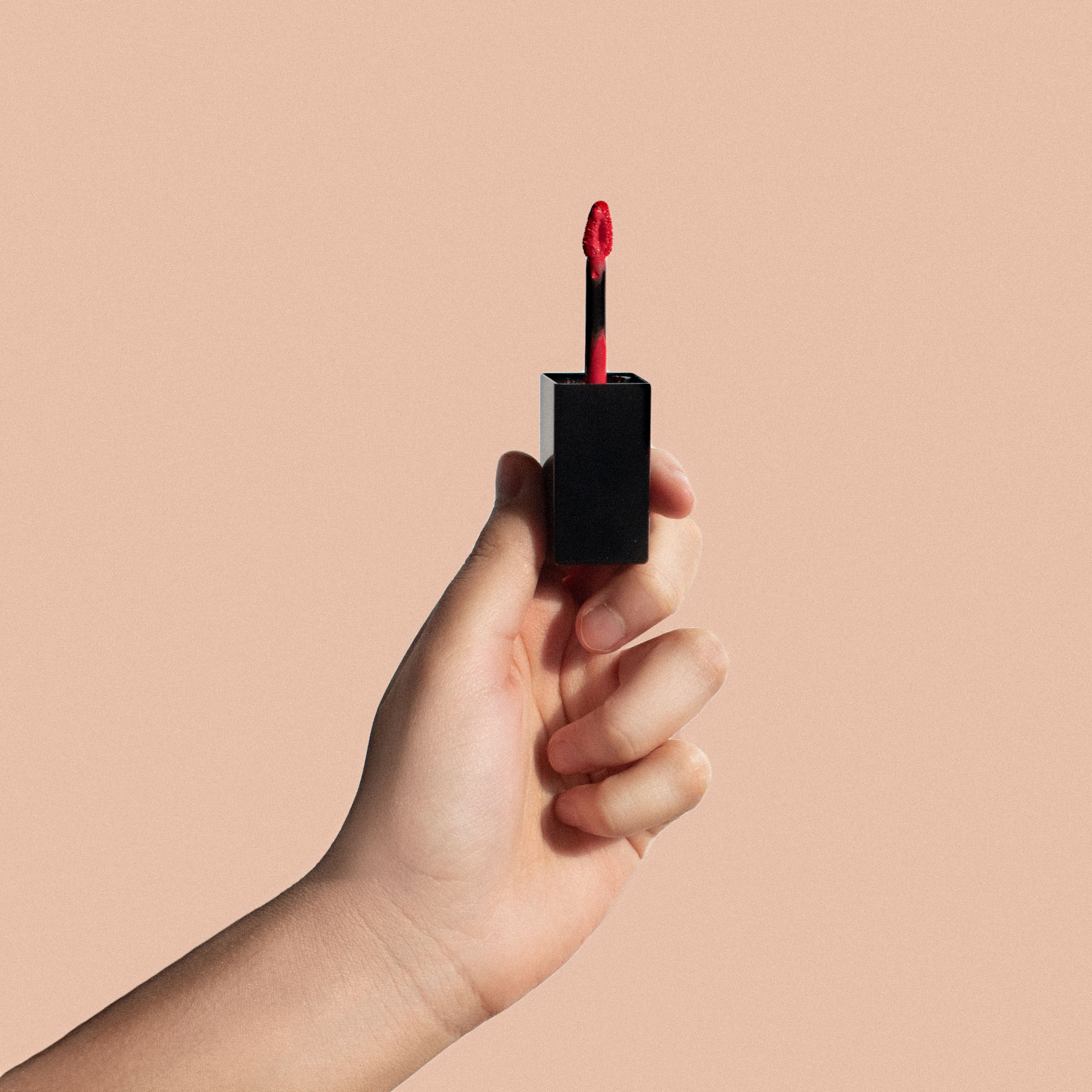 A tube of Matte Lip Stain in Dark Cherry with a doe-shaped applicator, showcasing its rich color and sleek design.