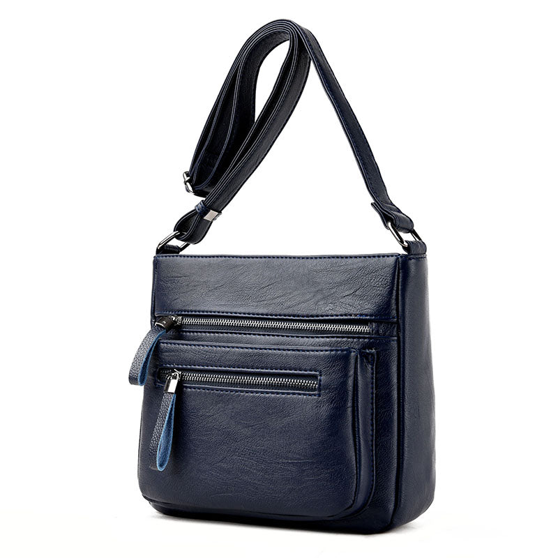 A stylish middle-aged women's soft leather shoulder bag in a box shape, featuring a zipper closure and trendy belt decoration, perfect for everyday use.