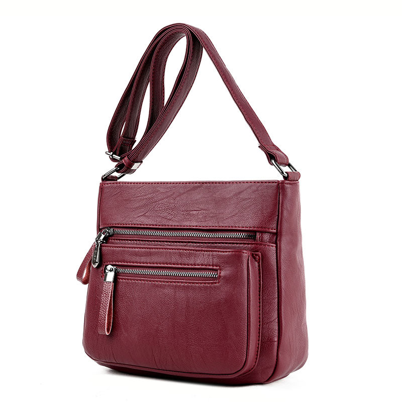 A stylish middle-aged women's soft leather shoulder bag in a box shape, featuring a zipper closure and trendy belt decoration, perfect for everyday use.