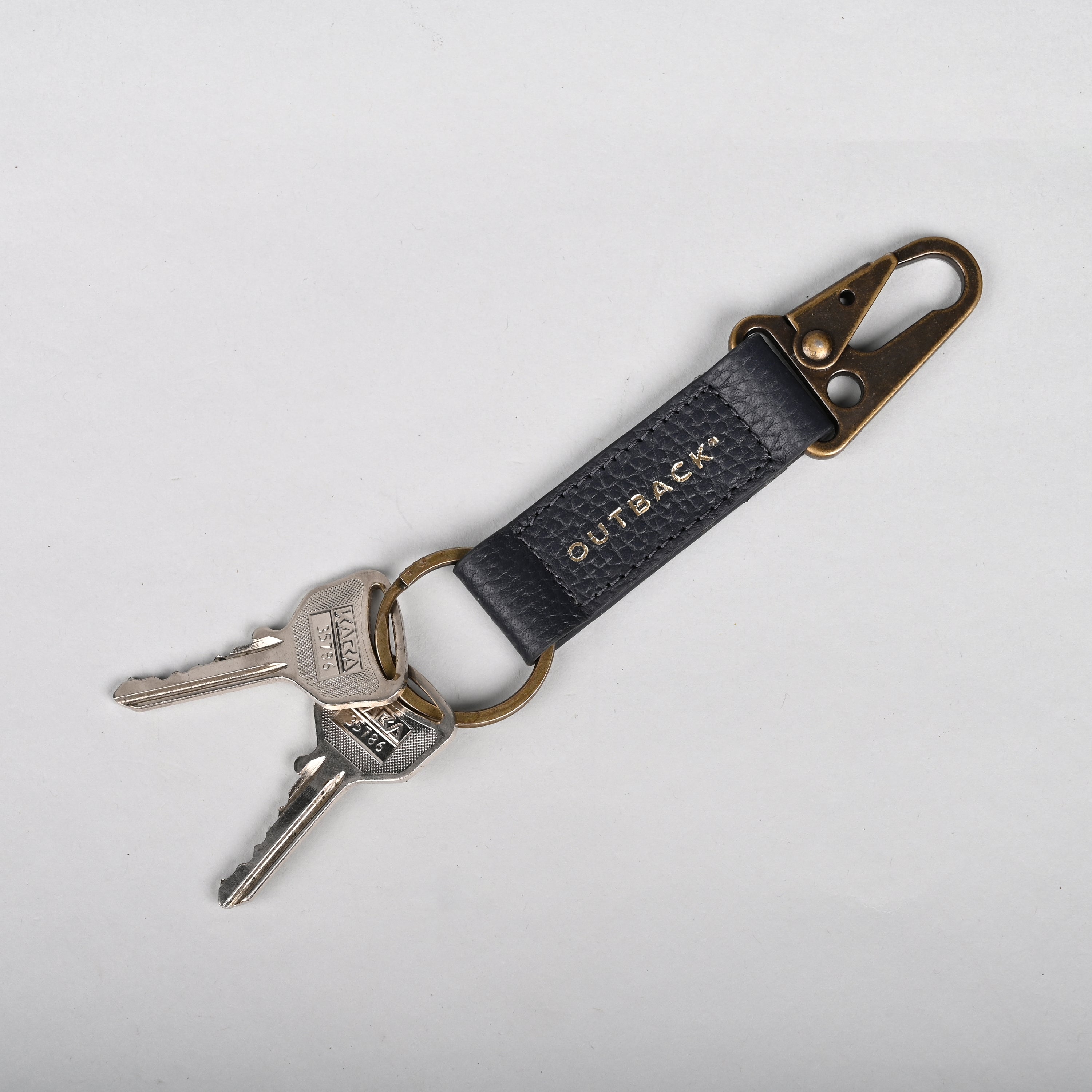 Performance Key Holder made from premium leather with antique brass hardware, showcasing its elegant design and snap hook mechanism.