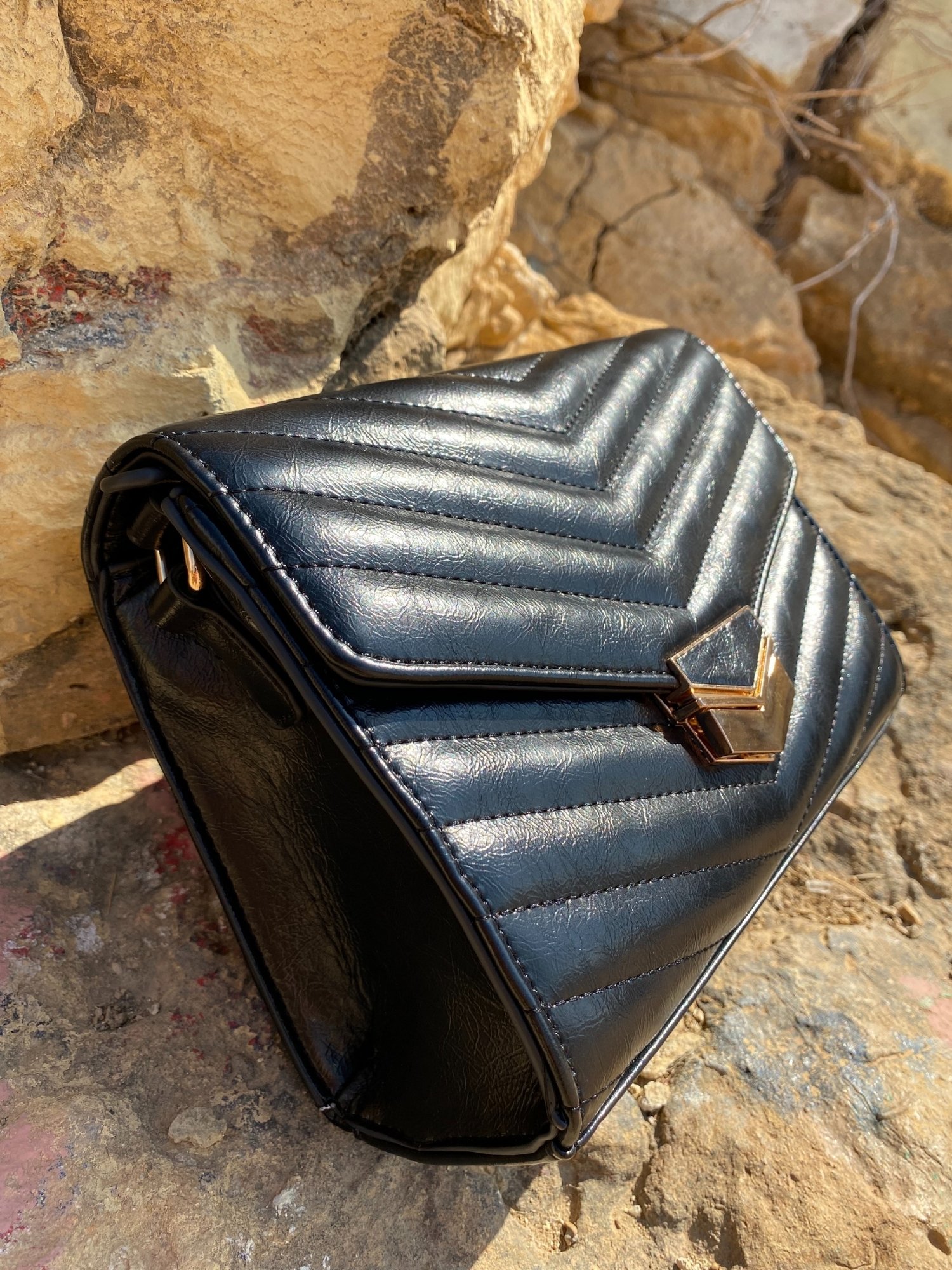 Stylish black quilted crossbody bag with adjustable strap and metal closure.