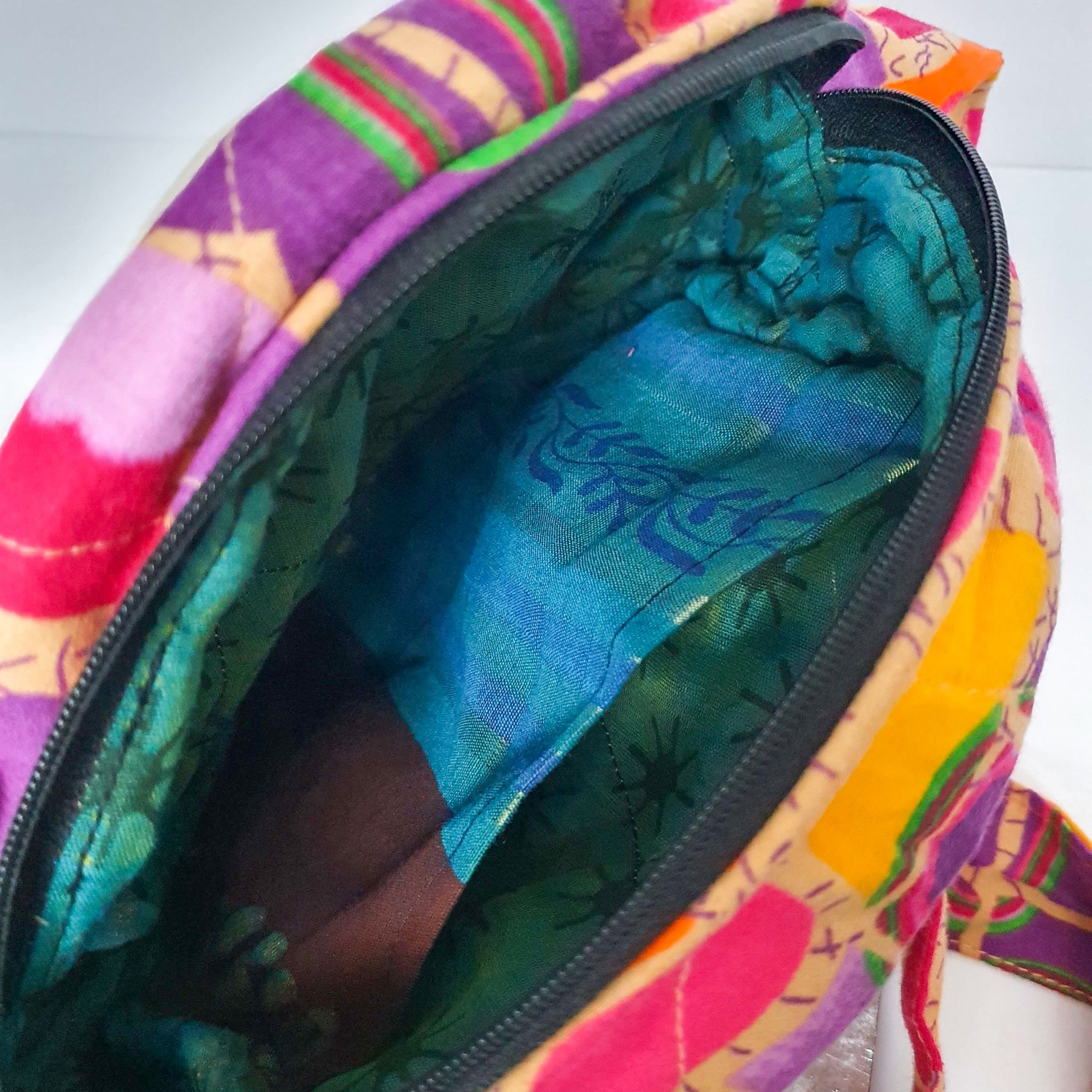 A vibrant round shoulder bag made from repurposed saris, showcasing unique patterns and colors, handcrafted by artisans in India.