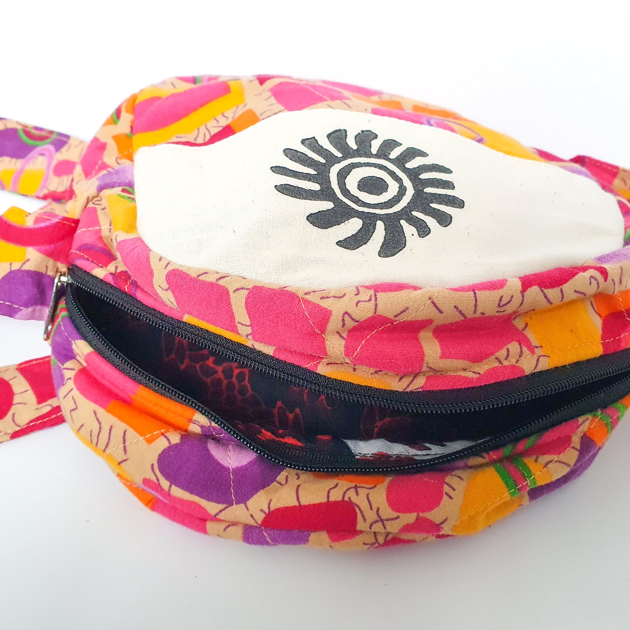 A vibrant round shoulder bag made from repurposed saris, showcasing unique patterns and colors, handcrafted by artisans in India.