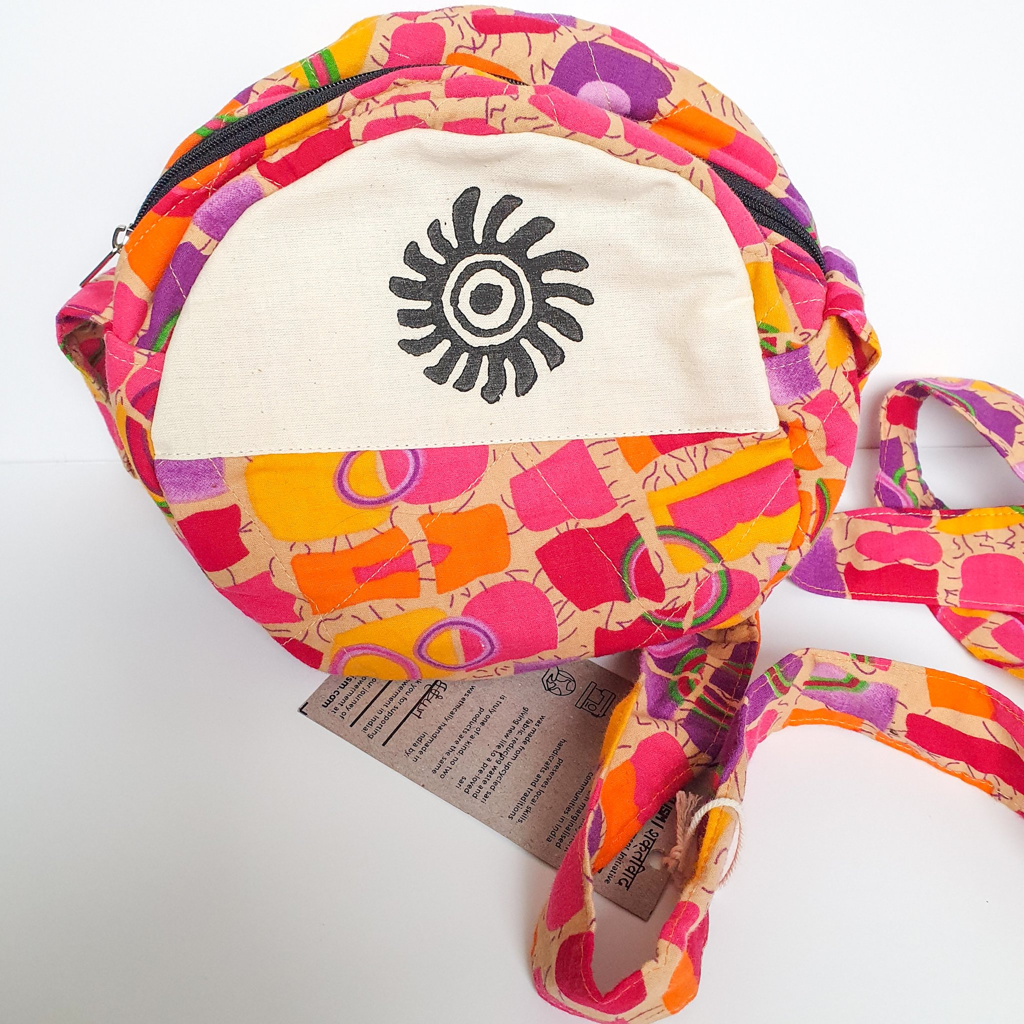 A vibrant round shoulder bag made from repurposed saris, showcasing unique patterns and colors, handcrafted by artisans in India.