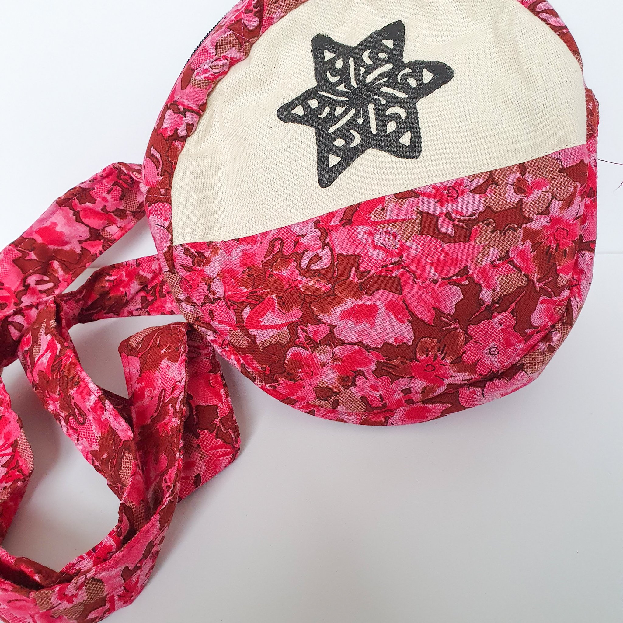 A vibrant round shoulder bag made from repurposed saris, showcasing unique patterns and colors, handcrafted by artisans in India.