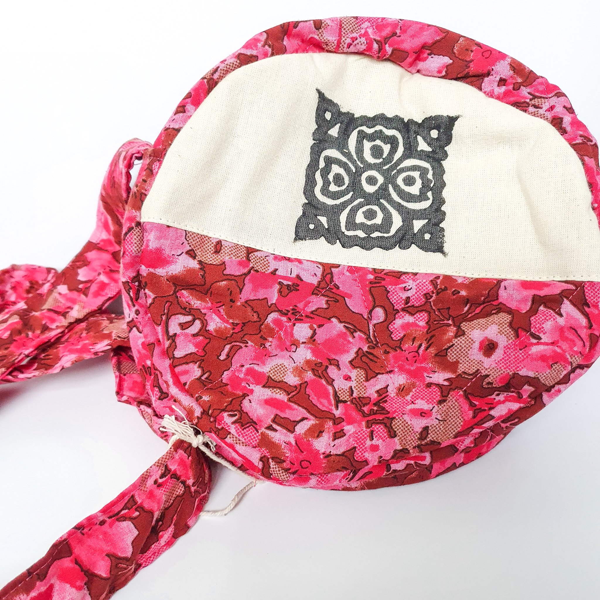 A vibrant round shoulder bag made from repurposed saris, showcasing unique patterns and colors, handcrafted by artisans in India.