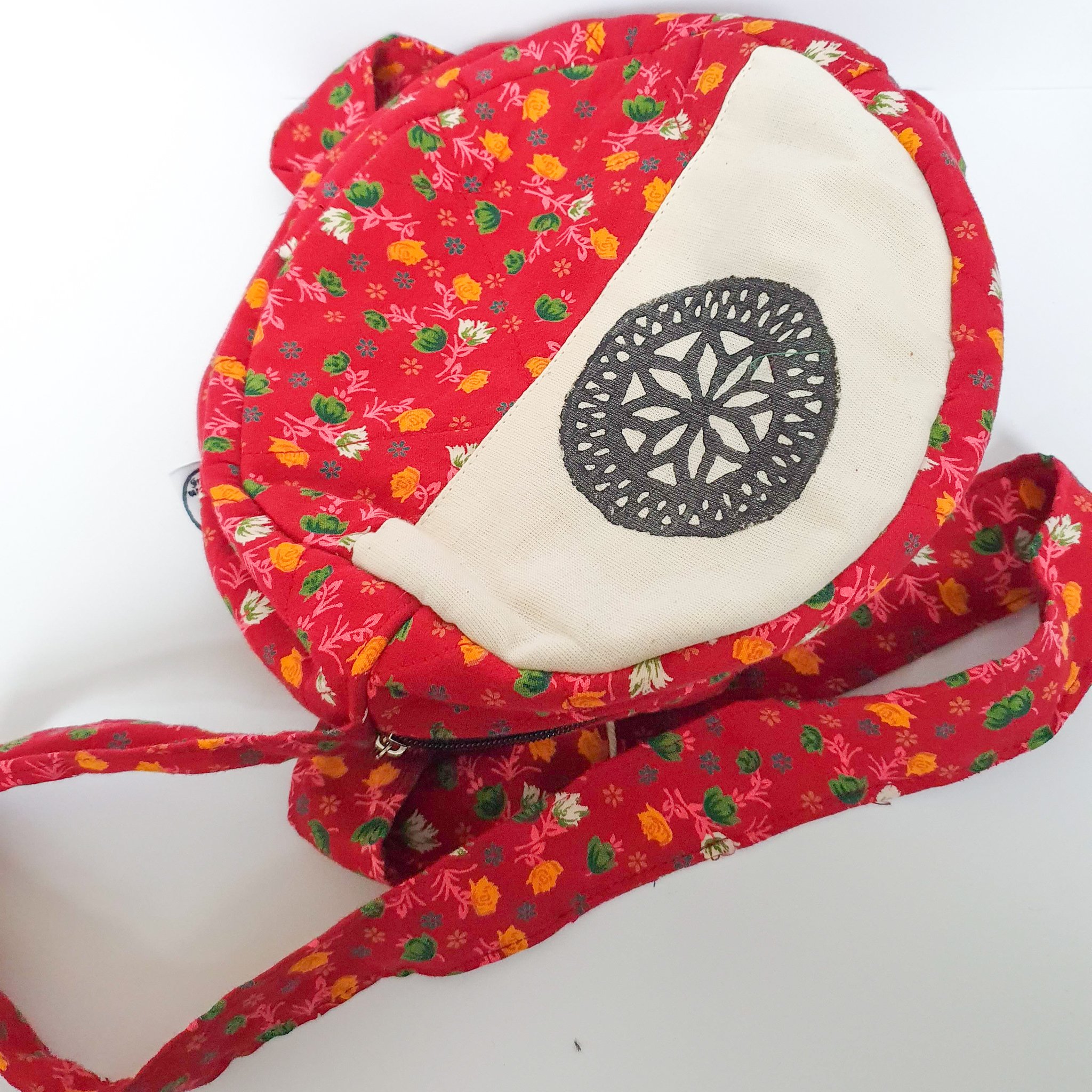 A vibrant round shoulder bag made from repurposed saris, showcasing unique patterns and colors, handcrafted by artisans in India.