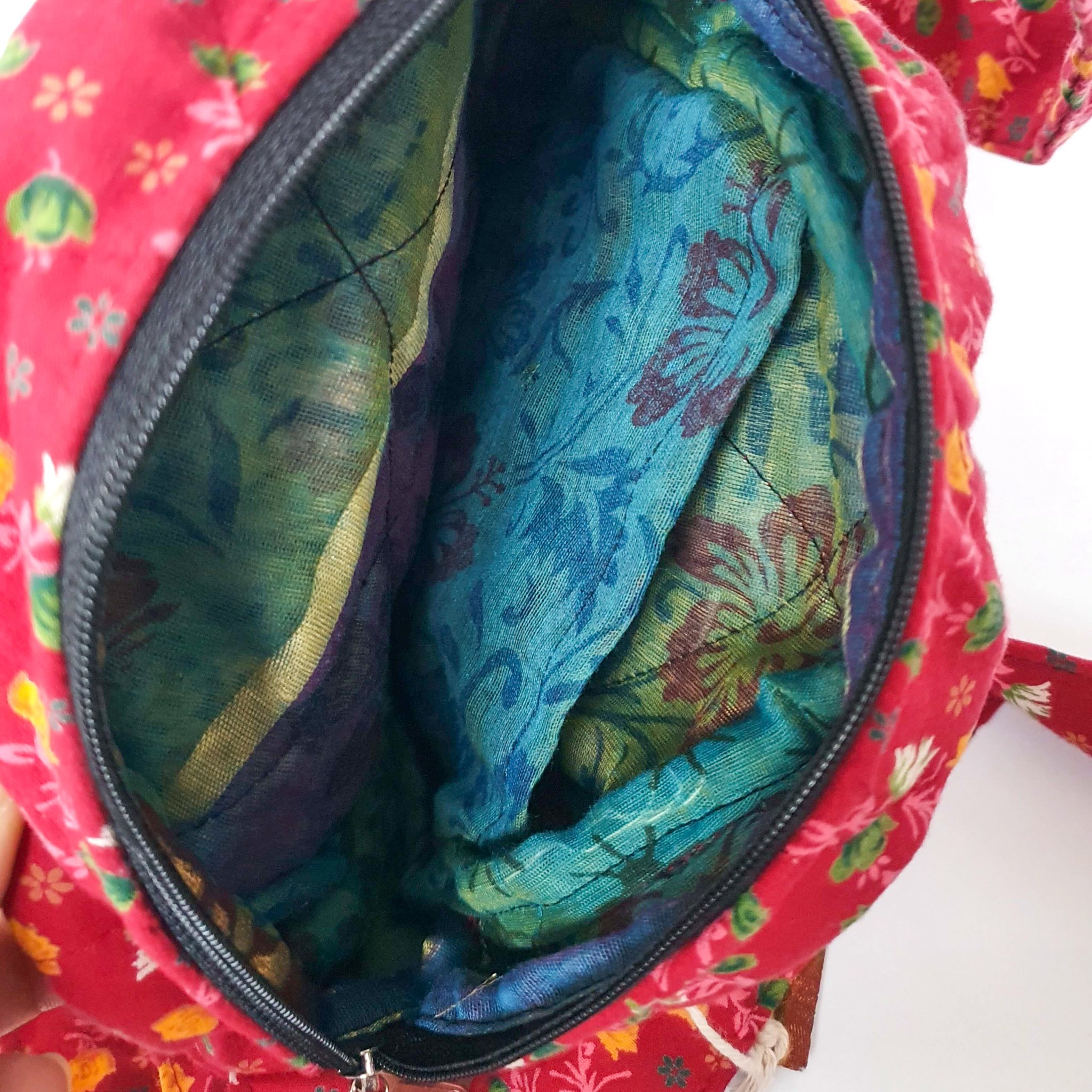 A vibrant round shoulder bag made from repurposed saris, showcasing unique patterns and colors, handcrafted by artisans in India.