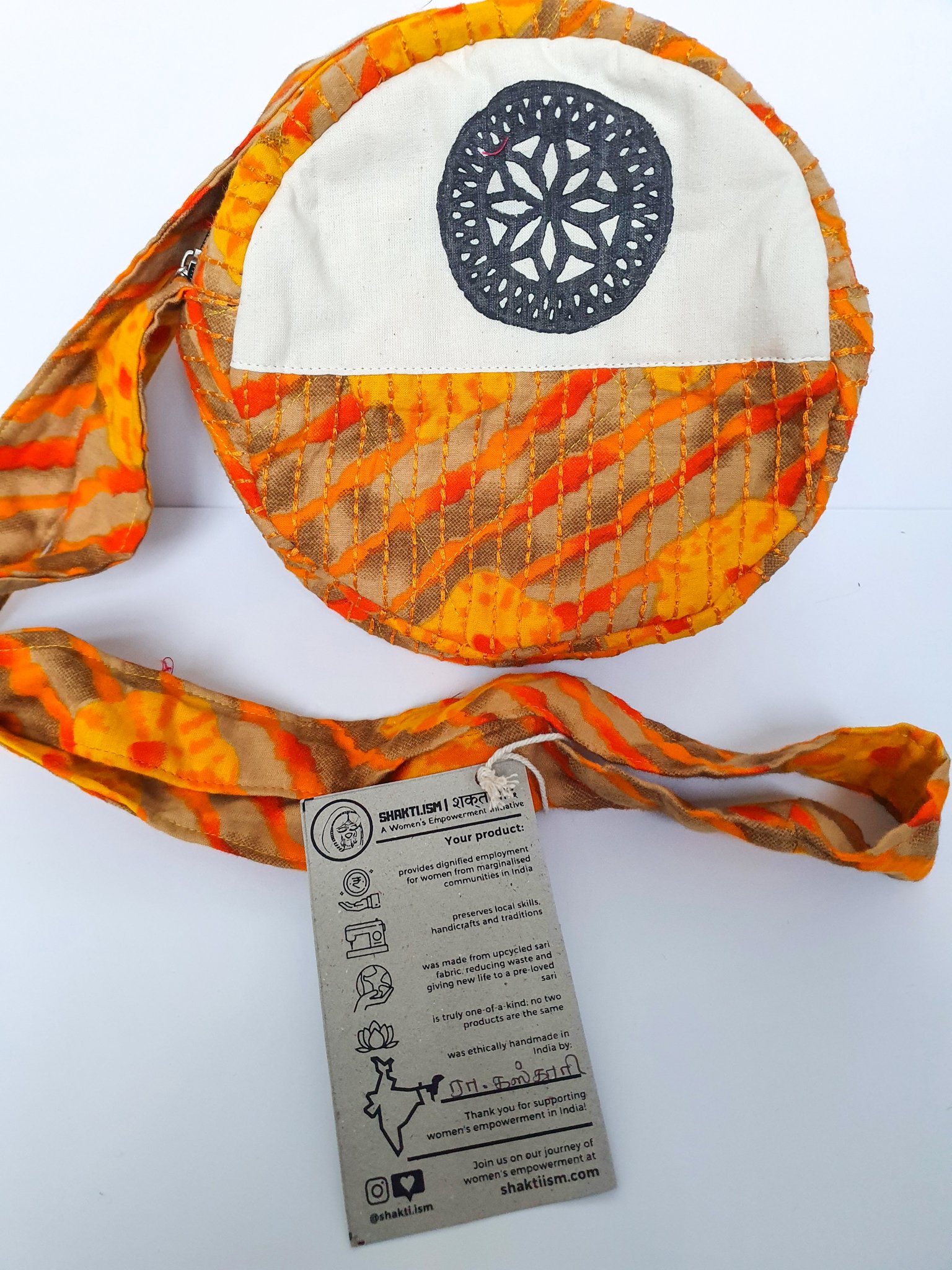 A vibrant round shoulder bag made from repurposed saris, showcasing unique patterns and colors, handcrafted by artisans in India.