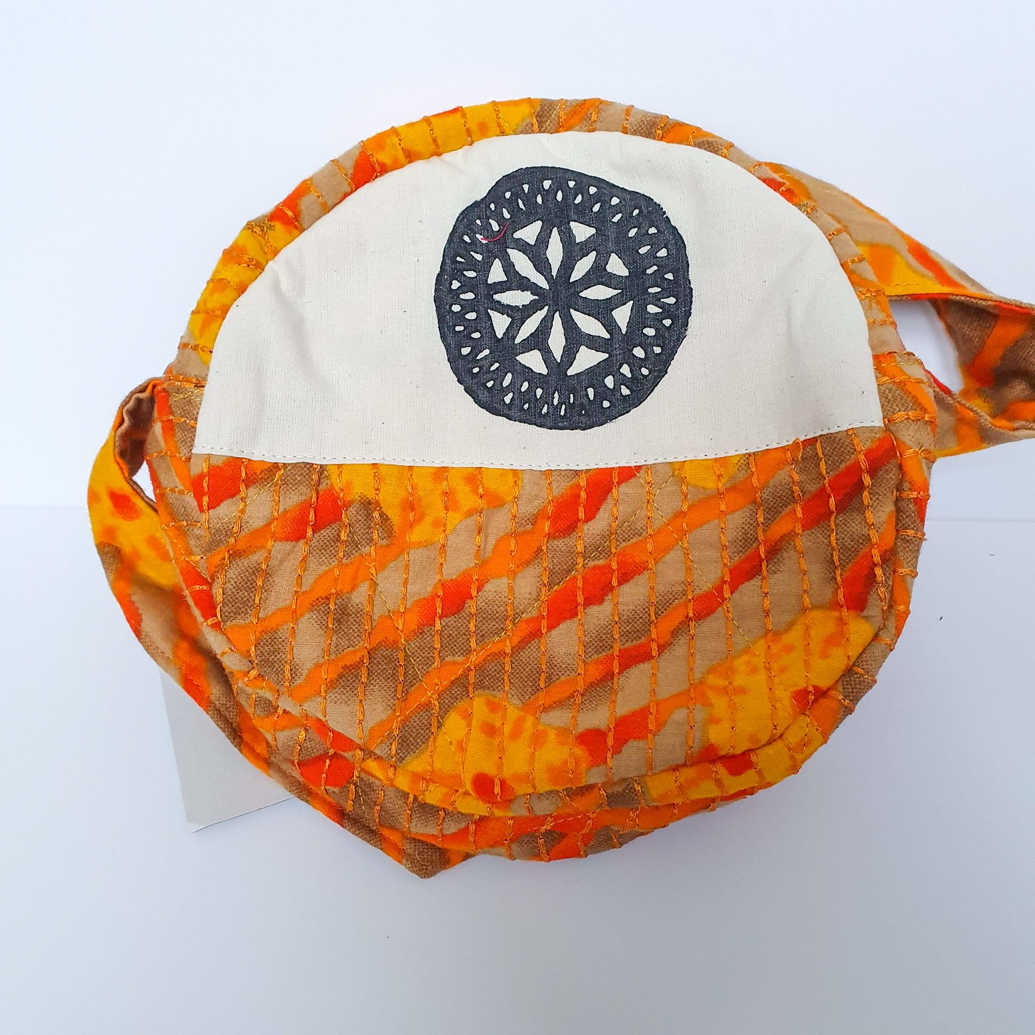 A vibrant round shoulder bag made from repurposed saris, showcasing unique patterns and colors, handcrafted by artisans in India.