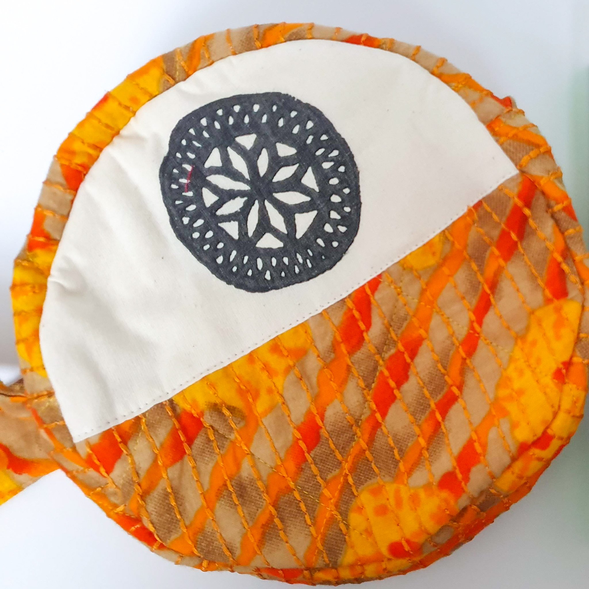 A vibrant round shoulder bag made from repurposed saris, showcasing unique patterns and colors, handcrafted by artisans in India.