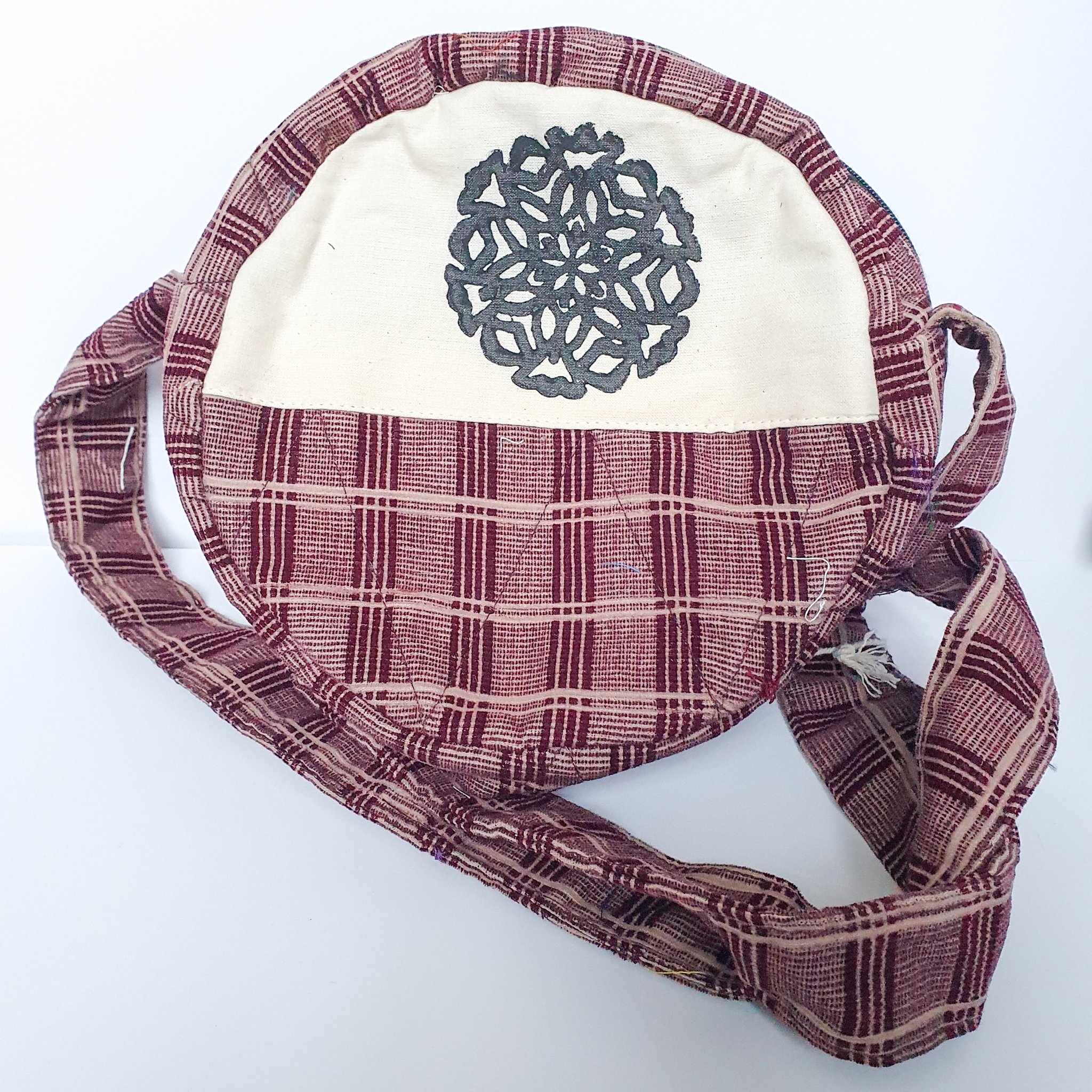 A vibrant round shoulder bag made from repurposed saris, showcasing unique patterns and colors, handcrafted by artisans in India.