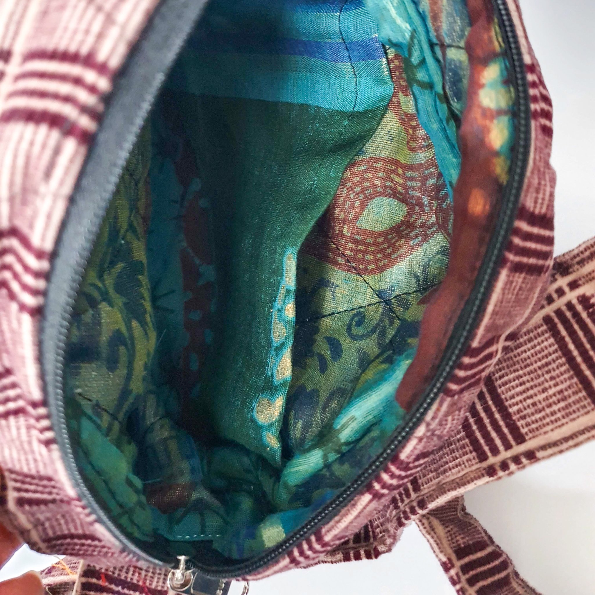 A vibrant round shoulder bag made from repurposed saris, showcasing unique patterns and colors, handcrafted by artisans in India.