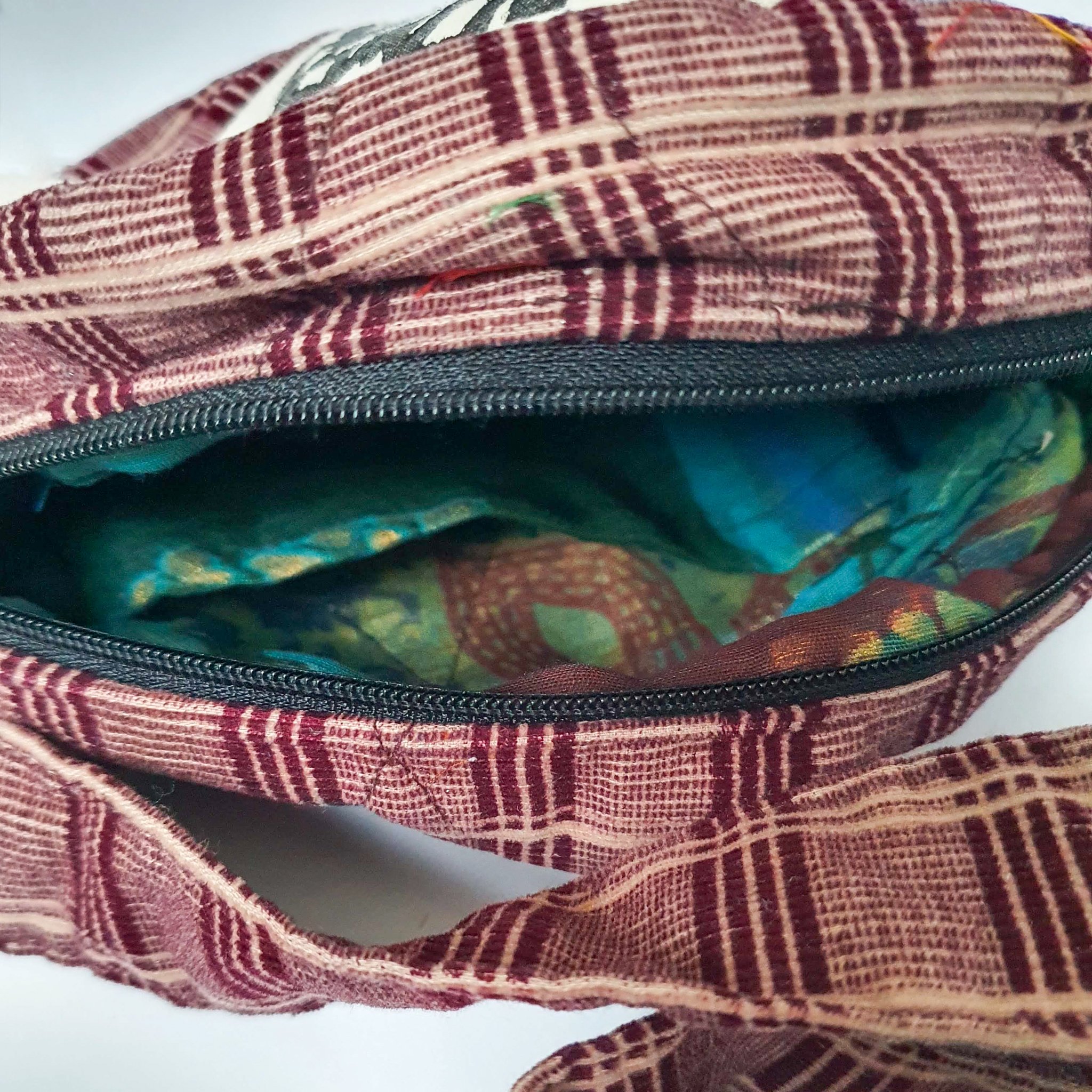 A vibrant round shoulder bag made from repurposed saris, showcasing unique patterns and colors, handcrafted by artisans in India.