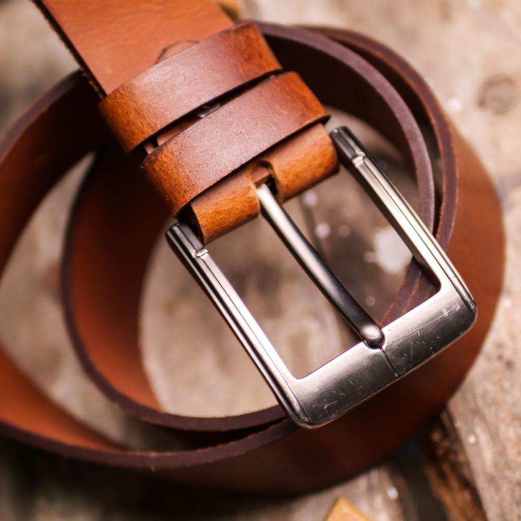 A rustic leather belt with double thread stitching and a single pin buckle, showcasing its quality and style.