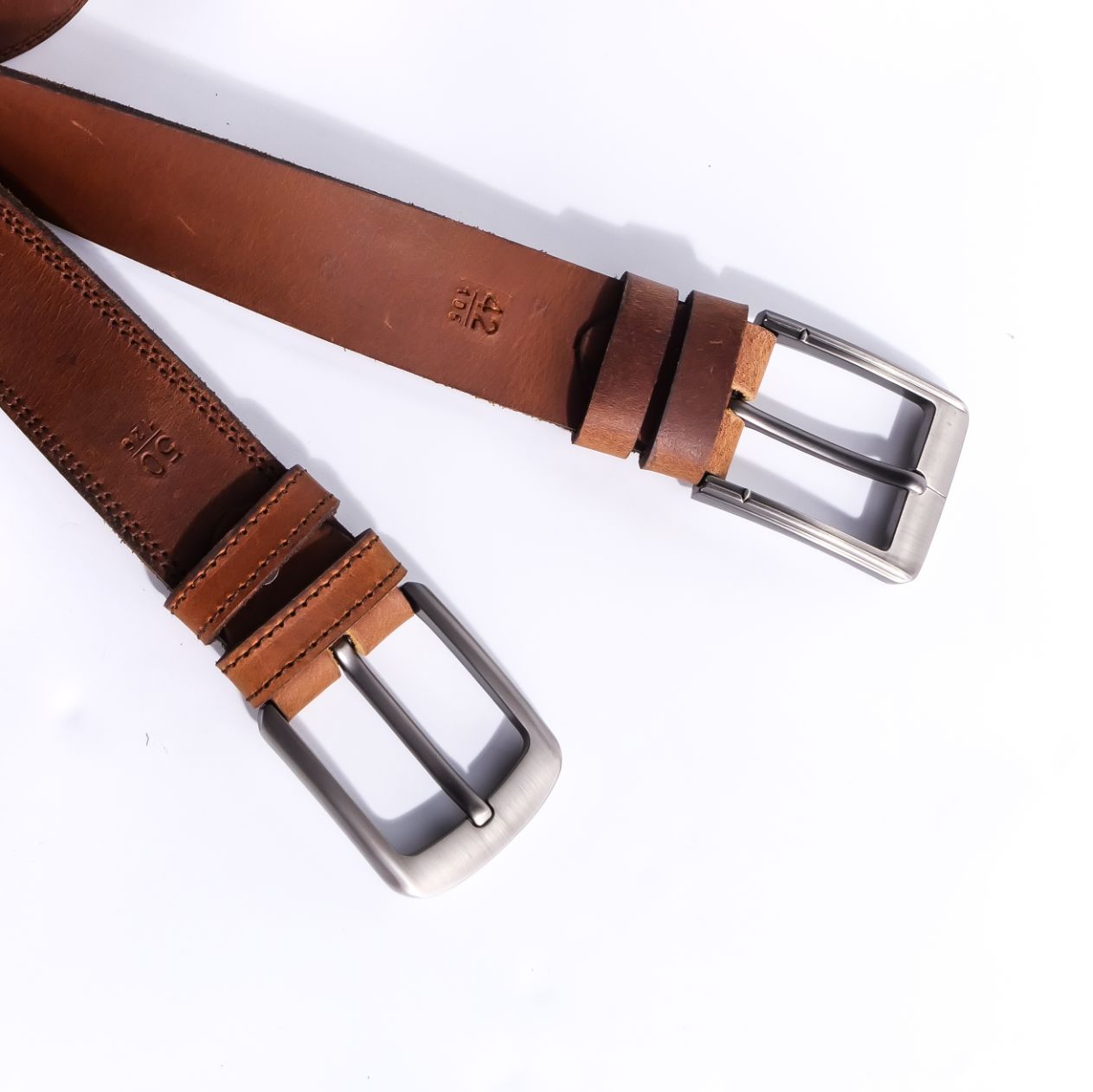 A rustic leather belt with double thread stitching and a single pin buckle, showcasing its quality and style.