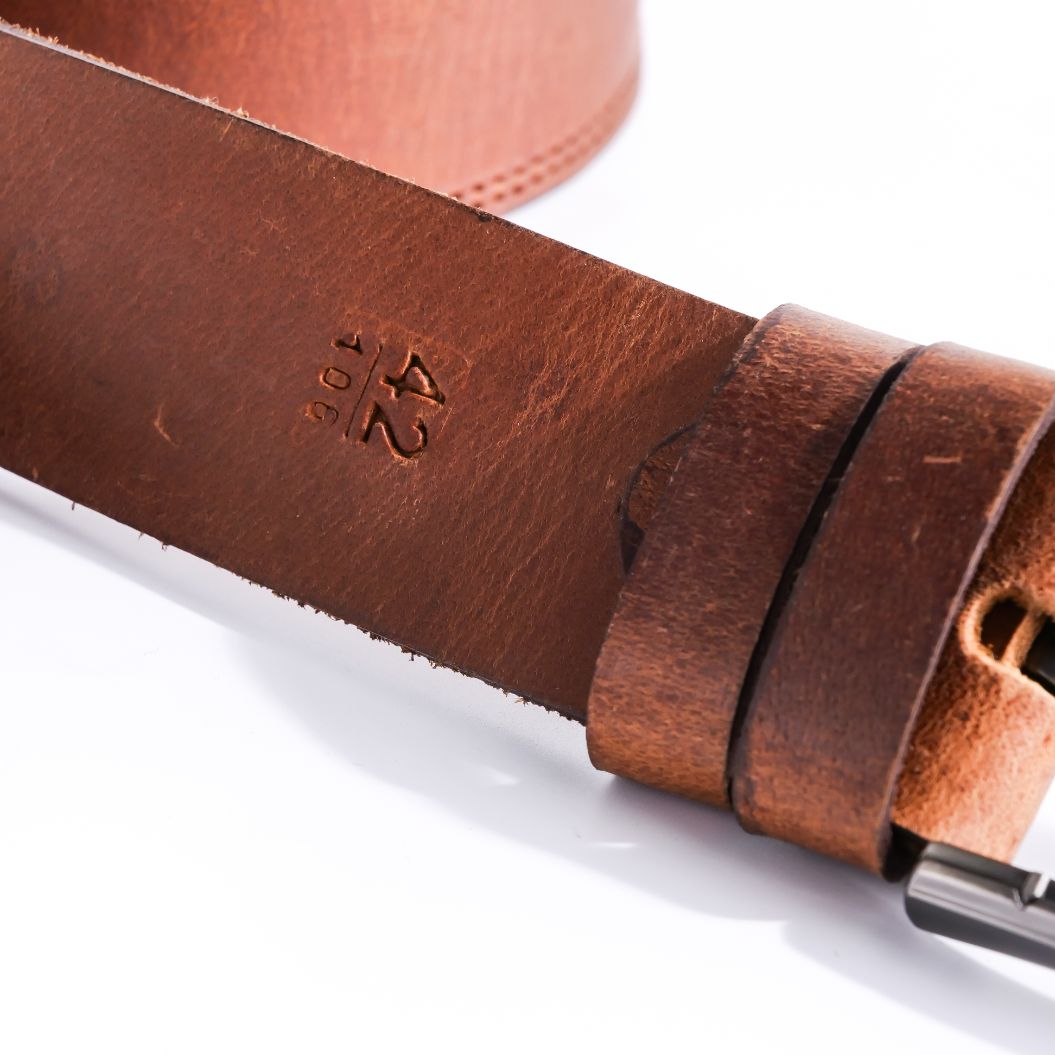 A rustic leather belt with double thread stitching and a single pin buckle, showcasing its quality and style.