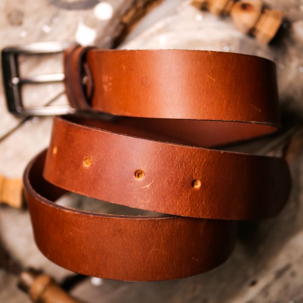 A rustic leather belt with double thread stitching and a single pin buckle, showcasing its quality and style.