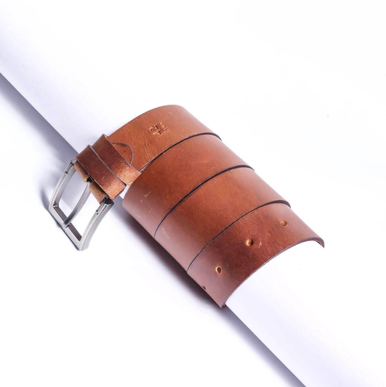 A rustic leather belt with double thread stitching and a single pin buckle, showcasing its quality and style.