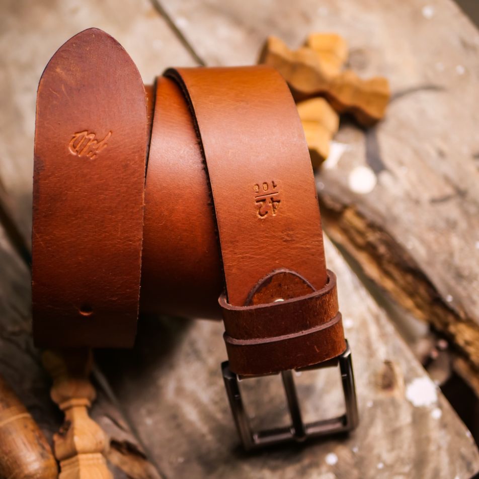 A rustic leather belt with double thread stitching and a single pin buckle, showcasing its quality and style.