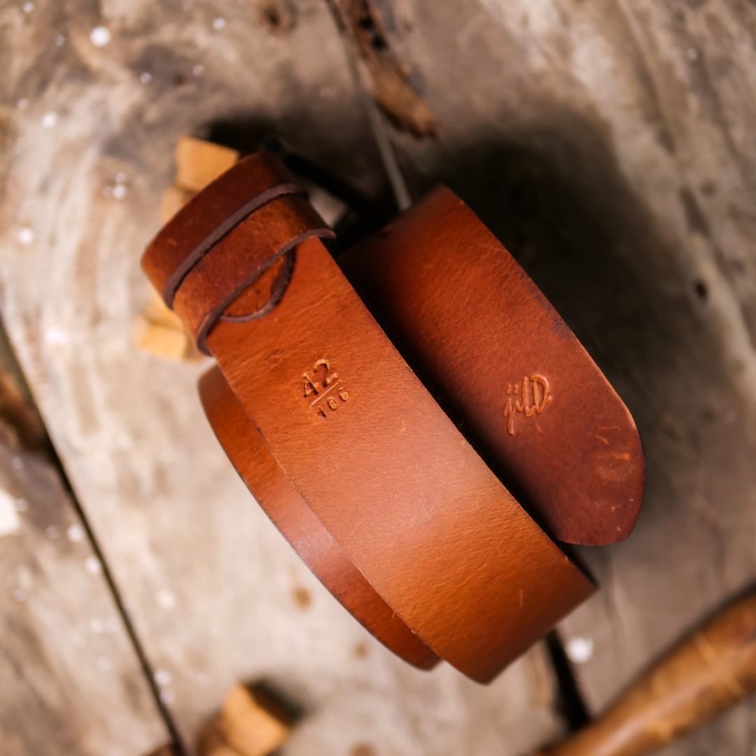 A rustic leather belt with double thread stitching and a single pin buckle, showcasing its quality and style.