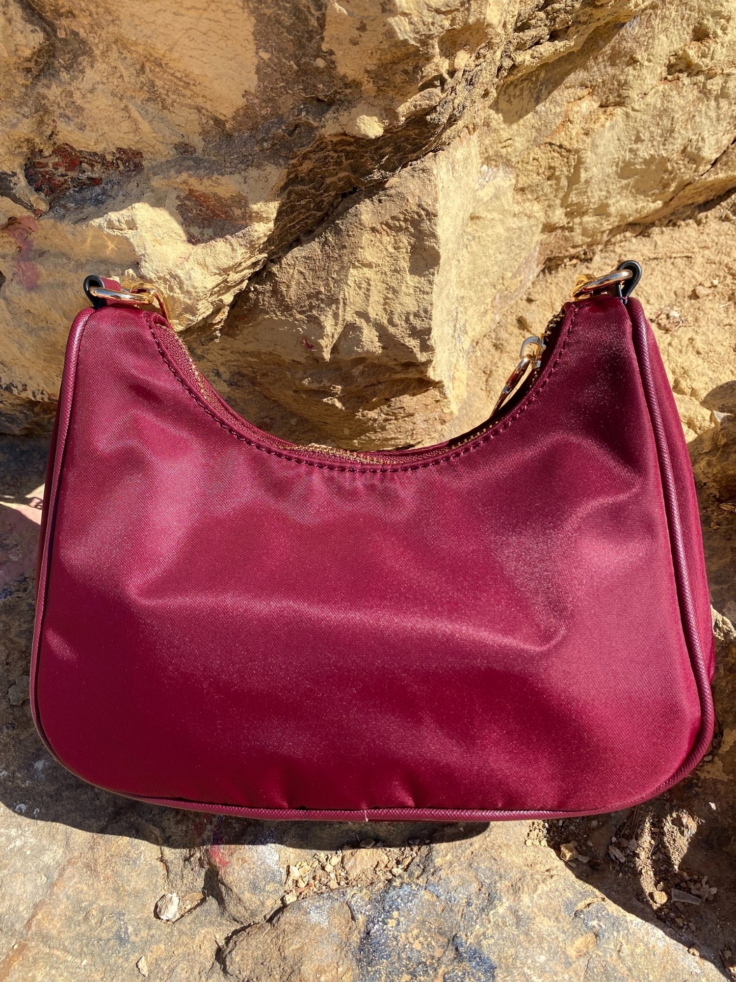 Stylish shoulder bag in magenta and beige with adjustable strap and zip closure, featuring a lined interior and zip pocket.