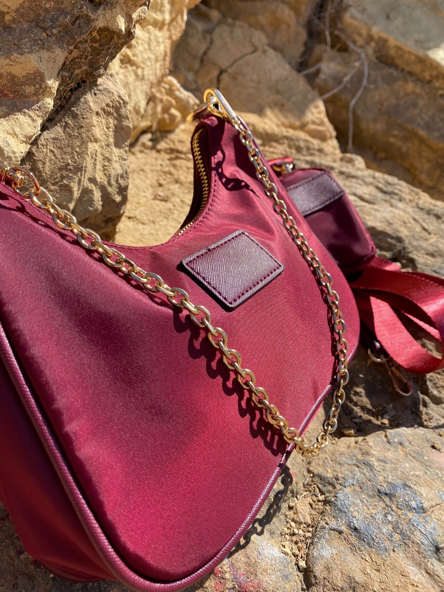 Stylish shoulder bag in magenta and beige with adjustable strap and zip closure, featuring a lined interior and zip pocket.