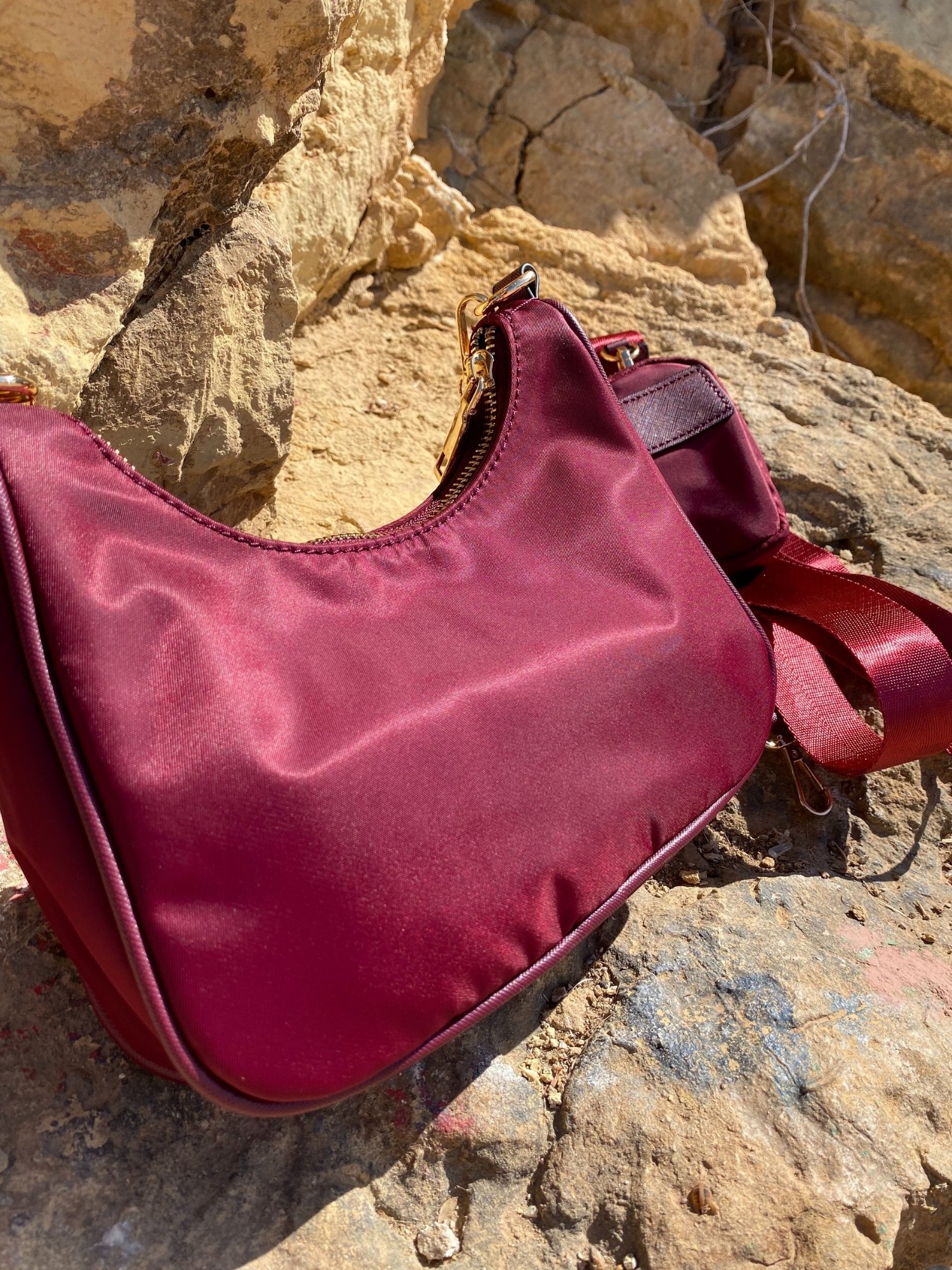 Stylish shoulder bag in magenta and beige with adjustable strap and zip closure, featuring a lined interior and zip pocket.