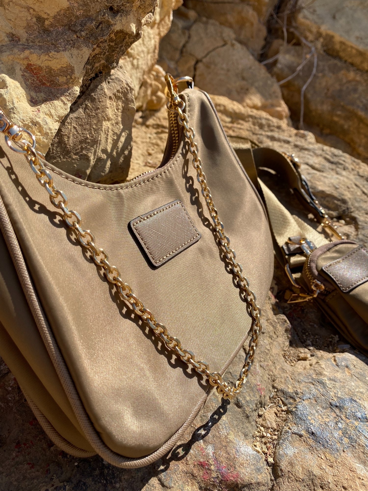 Stylish beige and magenta shoulder bag with chain, featuring adjustable strap and zip closure.