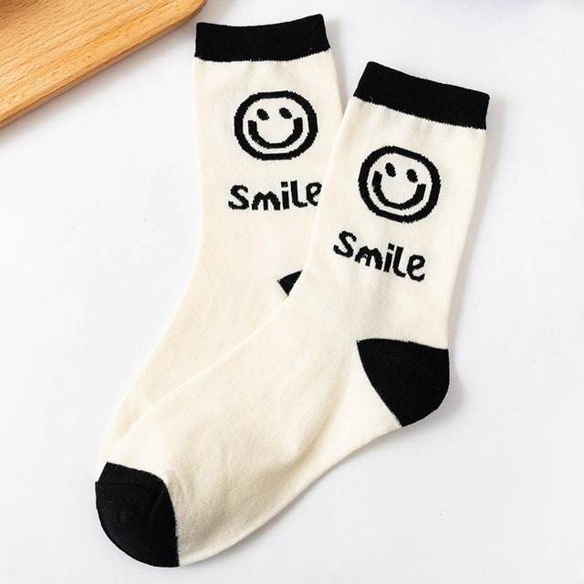 A pair of women's socks featuring a cheerful cartoon smiling face design, made from soft cotton material.