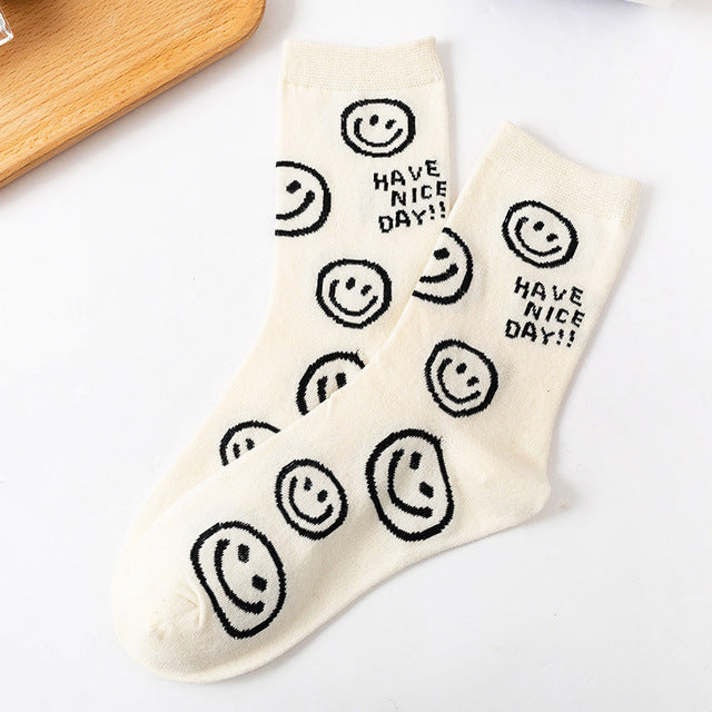 A pair of women's socks featuring a cheerful cartoon smiling face design, made from soft cotton material.