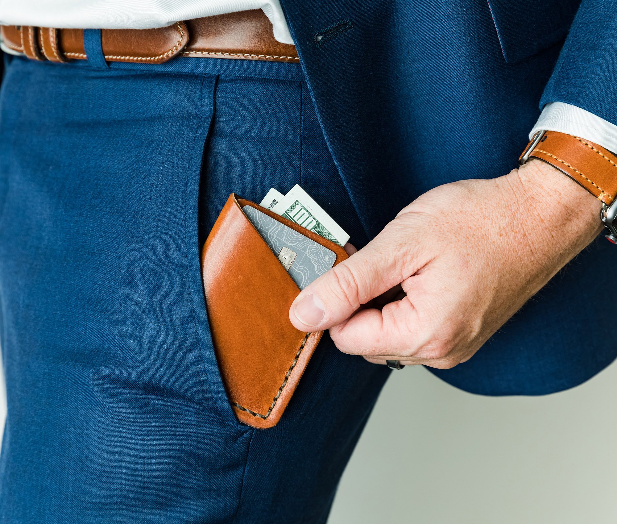 Tall Minimalist Wallet made of genuine full grain leather, featuring two card slots and a center cash slot, displayed with a muslin bag.