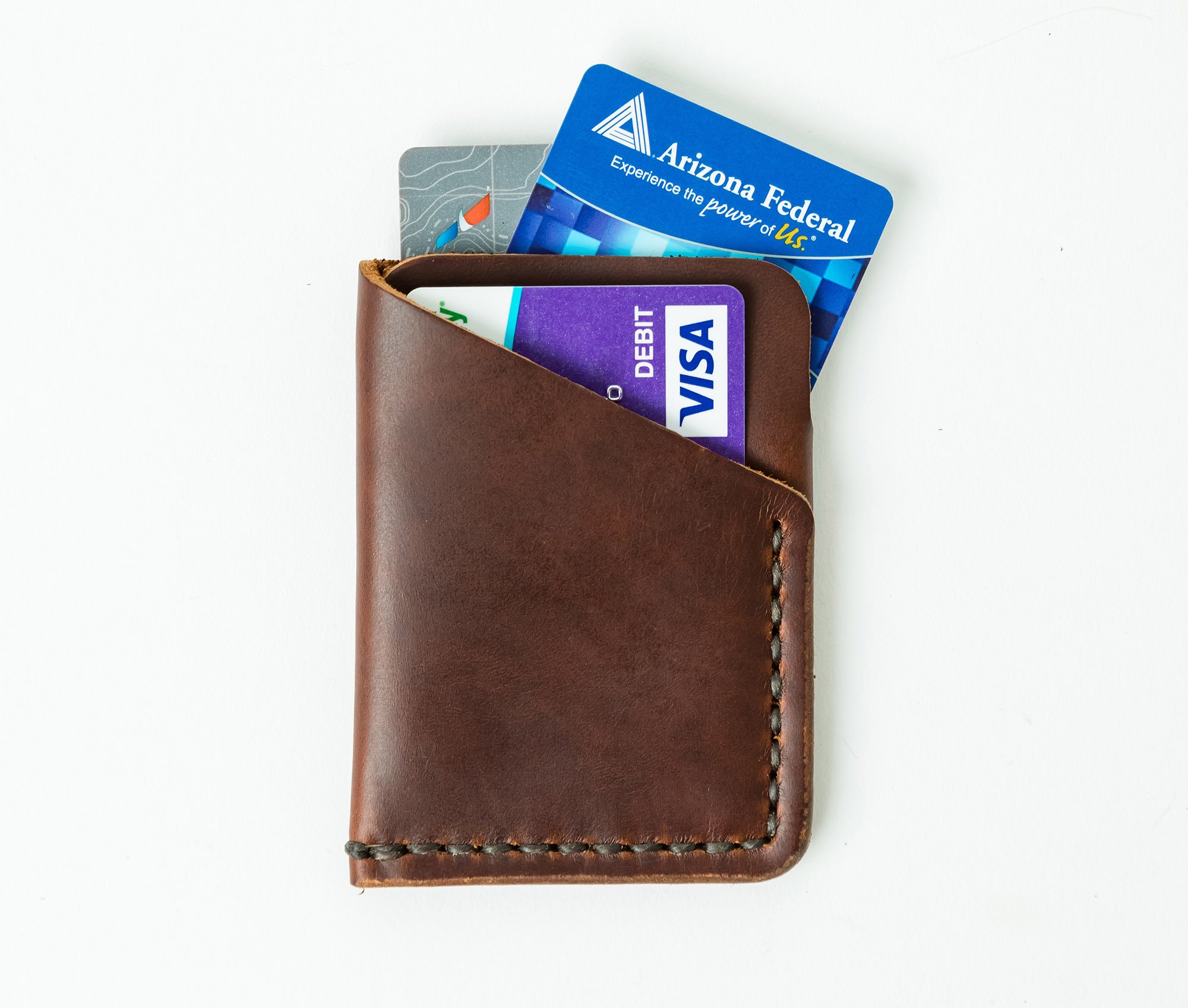 Tall Minimalist Wallet made of genuine full grain leather, featuring two card slots and a center cash slot, displayed with a muslin bag.