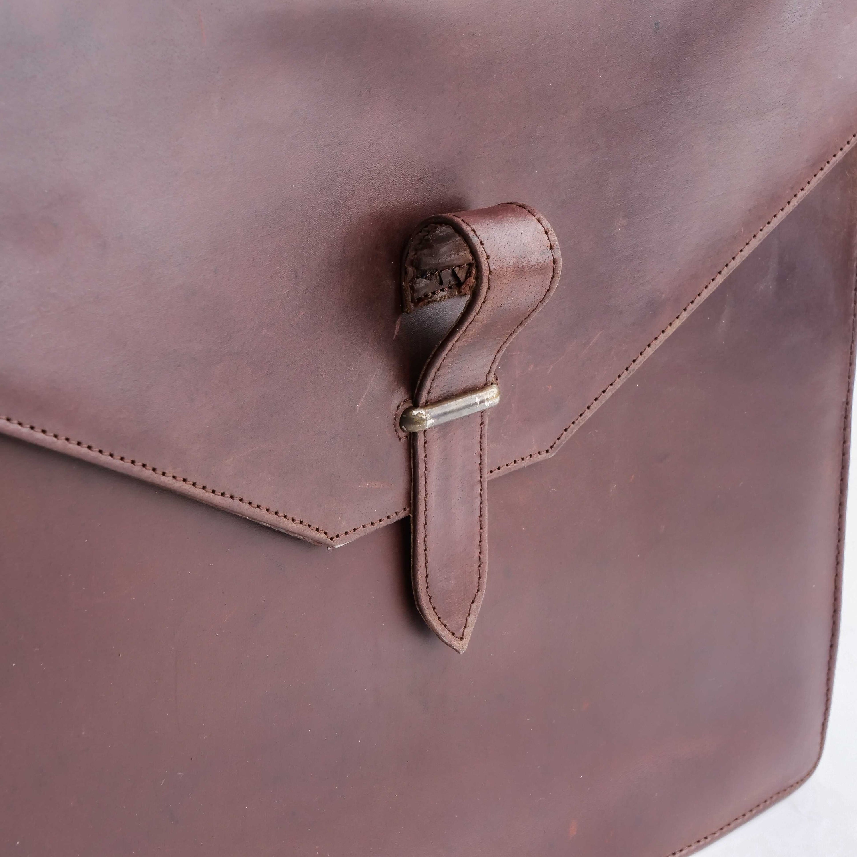 A stylish dark brown corporate pure leather bag with adjustable shoulder strap and top handle, showcasing its spacious compartments and elegant design.