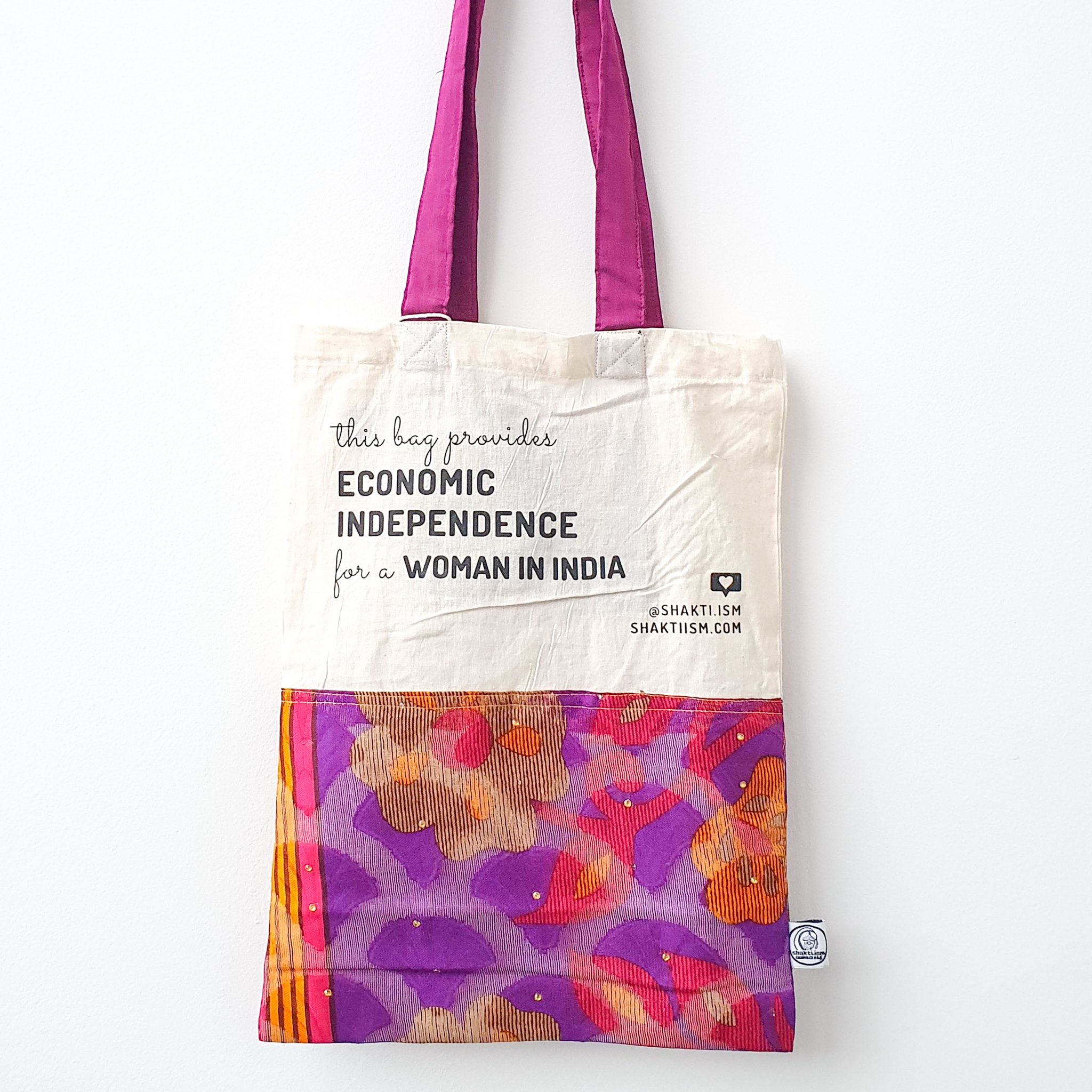 A vibrant Independence sari tote bag handcrafted from repurposed sari fabric, showcasing unique patterns and colors, with a message promoting women's economic independence.